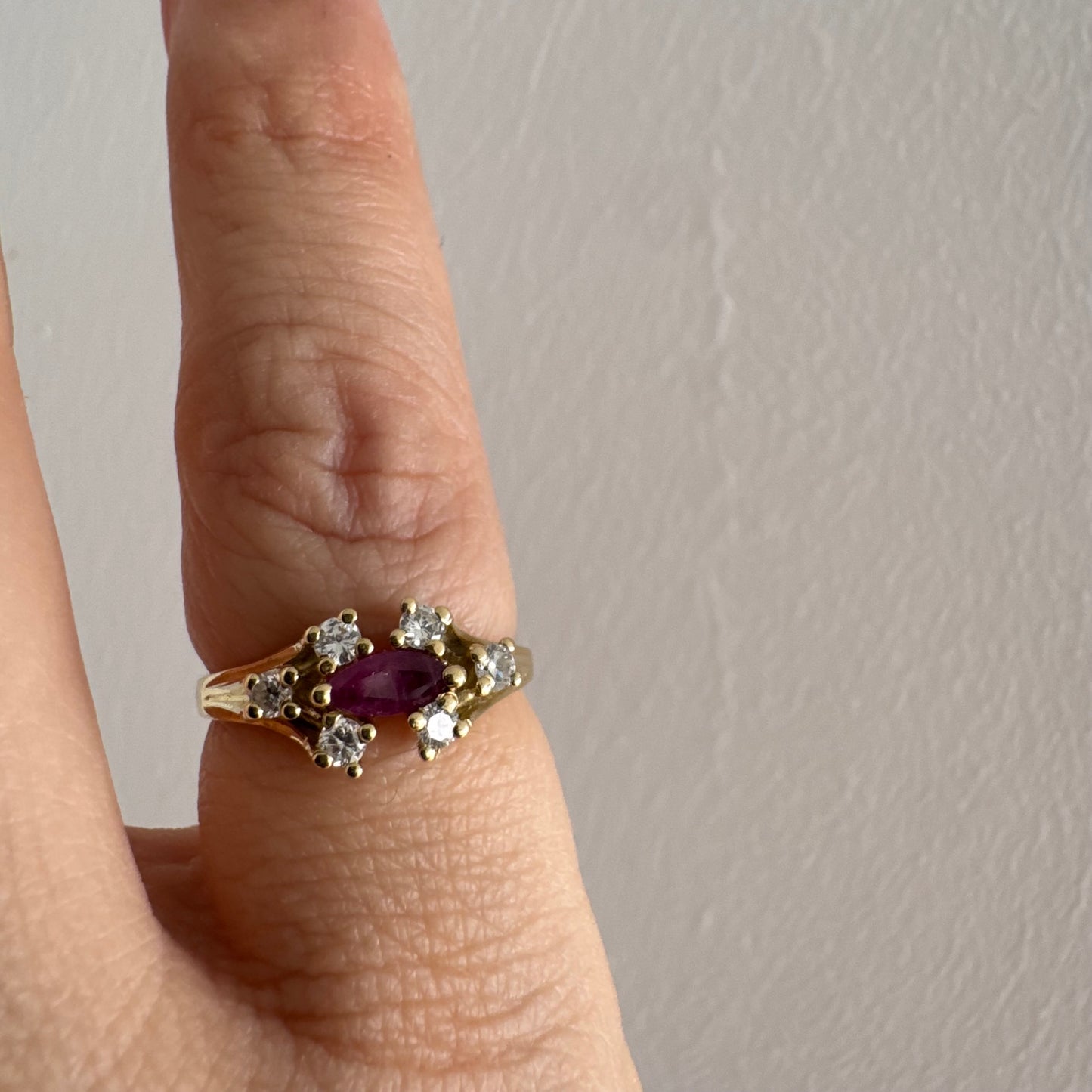 טבעת זהב צהוב 18 קראט משובצת אבן רובי בחיתוך מרקיזה בגוון מוקפת יהלומים בחיתוך עגול משני הצדדים.