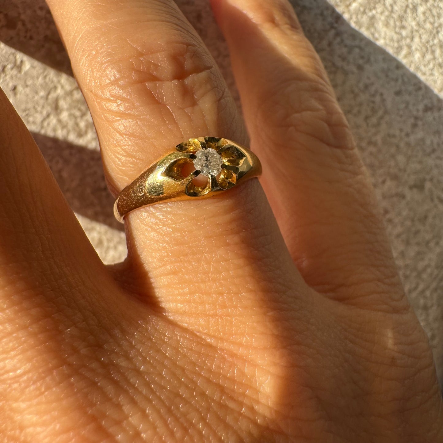 טבעת זהב צהוב 18 קראט בעיצוב פרח עדין, משובצת יהלום מרכזי בתוך עלי כותרת פתוחים.