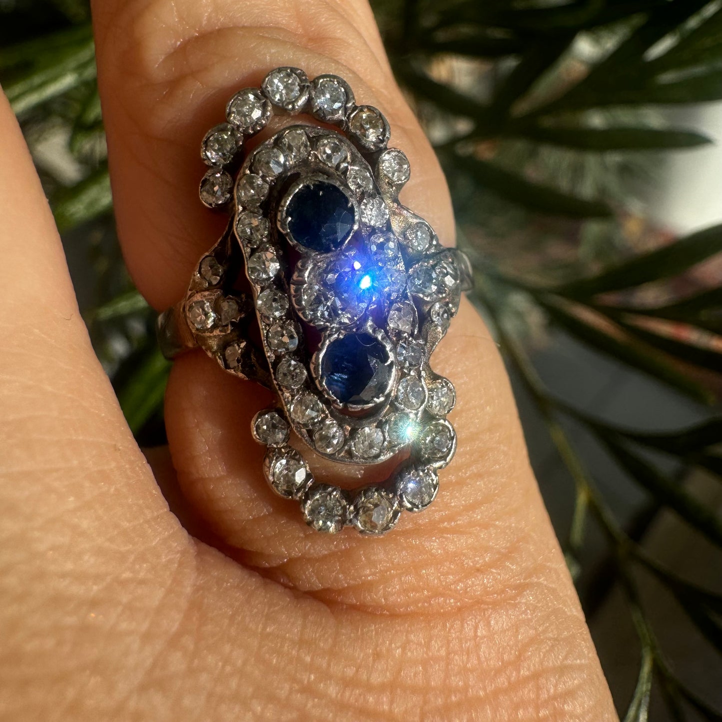 14K gold Antique featuring a stunning trio of gemstones - two deep blue Sapphires surrounding a brilliant old-cut Diamonds