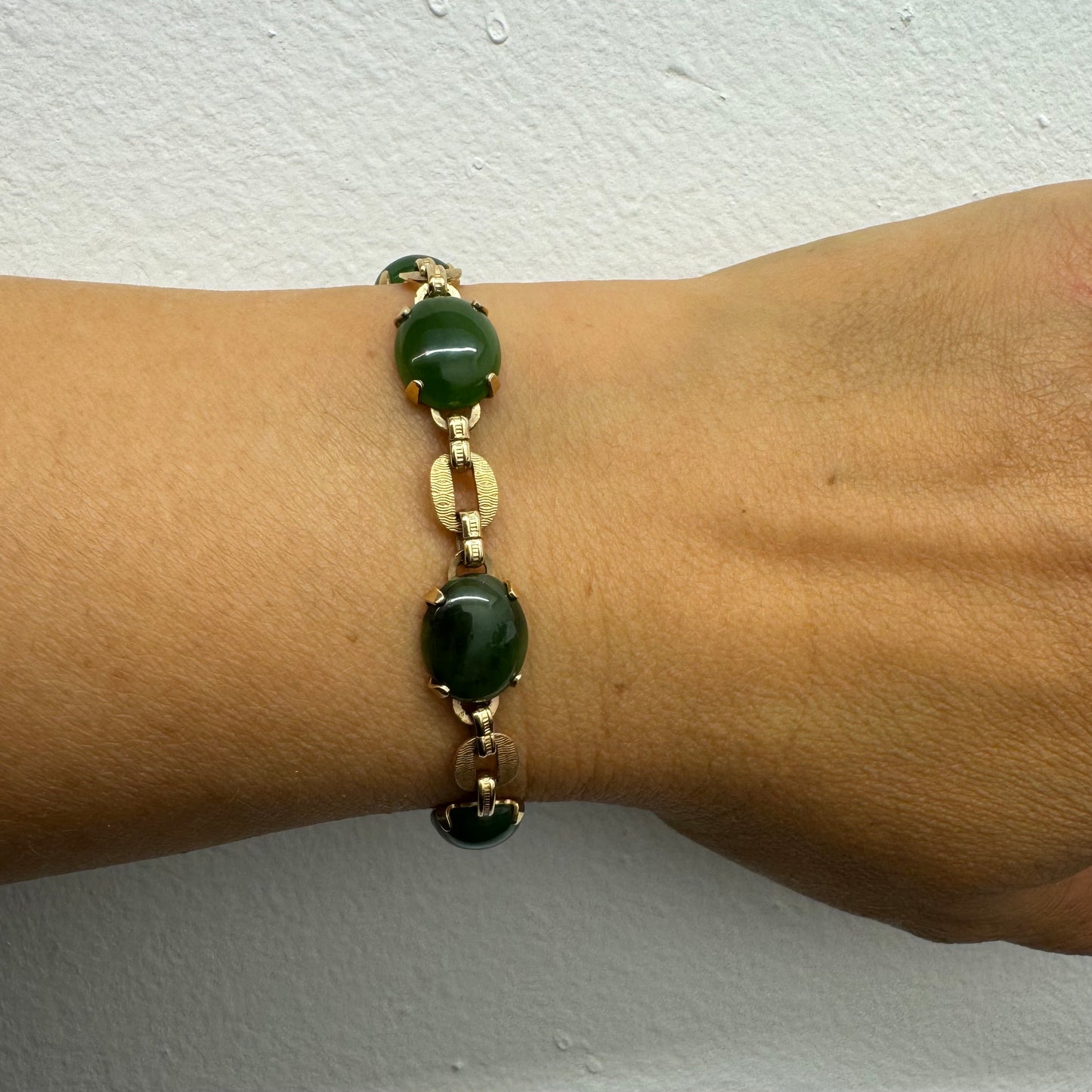 צמיד זהב צהוב 14 קראט משובץ באבני ג’ייד ירוקות בחיתוך קבושון (cabochon) בעיצוב אליפטי, המחוברות ביניהן בחוליות זהב עם טקסטורה מעניינת.