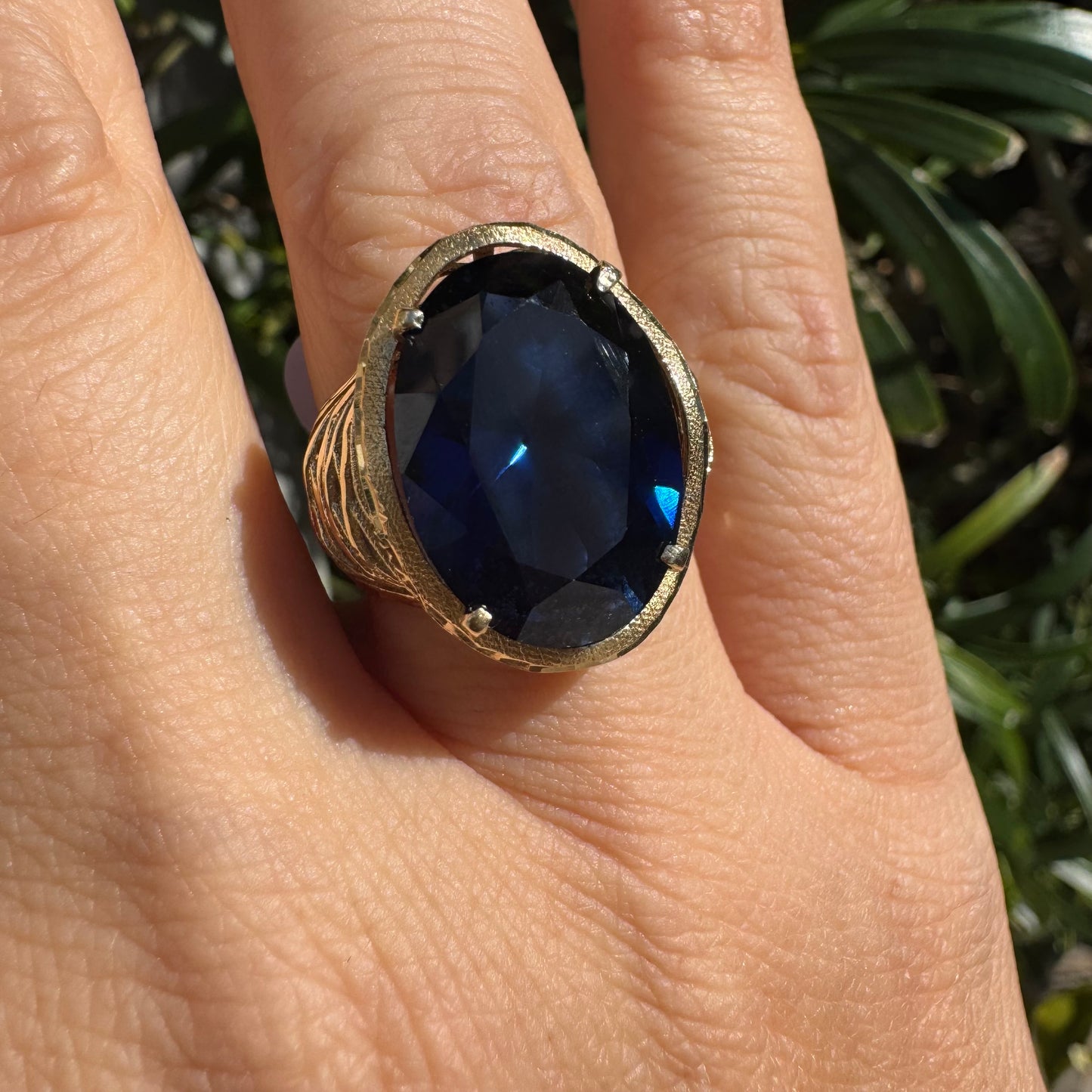 14K gold ring set with a deep navy-blue oval Sapphire in a dramatic openwork setting
