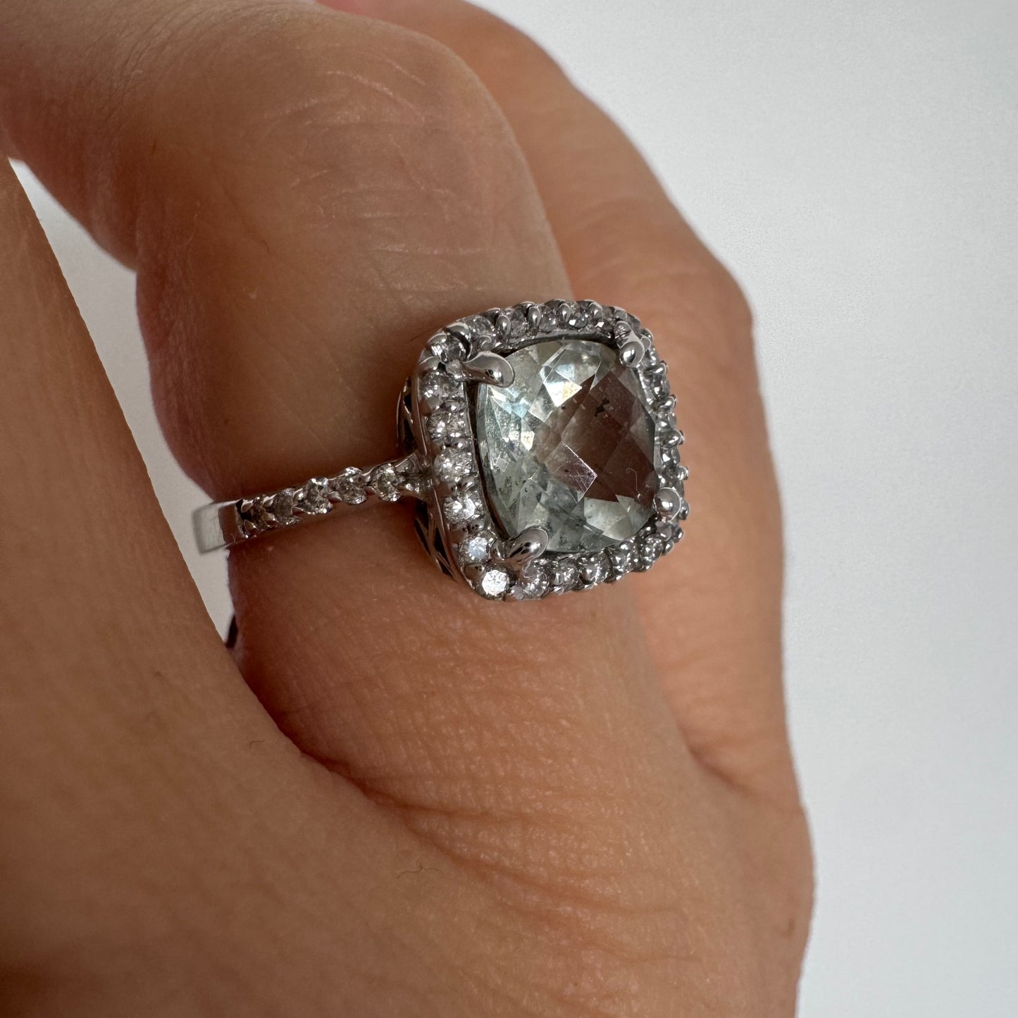 טבעת זהב לבן 14 קראט משובצת באבן אקוומרין בגוון תכלת ומוקפת במסגרת כפולה של יהלומים עגולים מנצנצים.