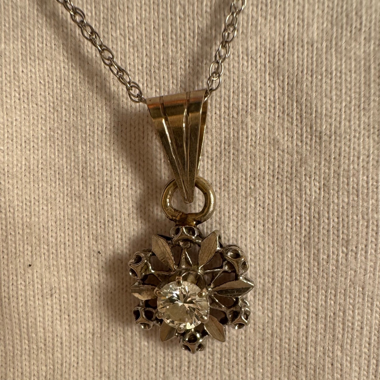 תליון זהב 14 קראט משובץ יהלום מרכזי בעיצוב פרח עדין ומלא נוכחות.