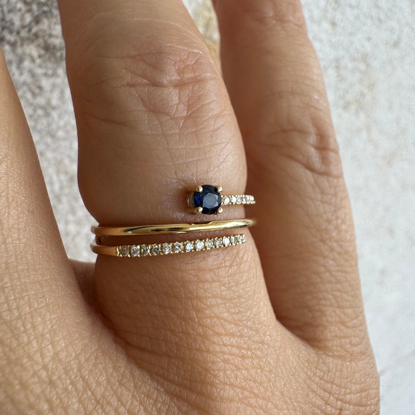 טבעת זהב צהוב 14 קראט משובצת אבן ספיר כחולה ויהלומים נוצצים בשורות עדינות.