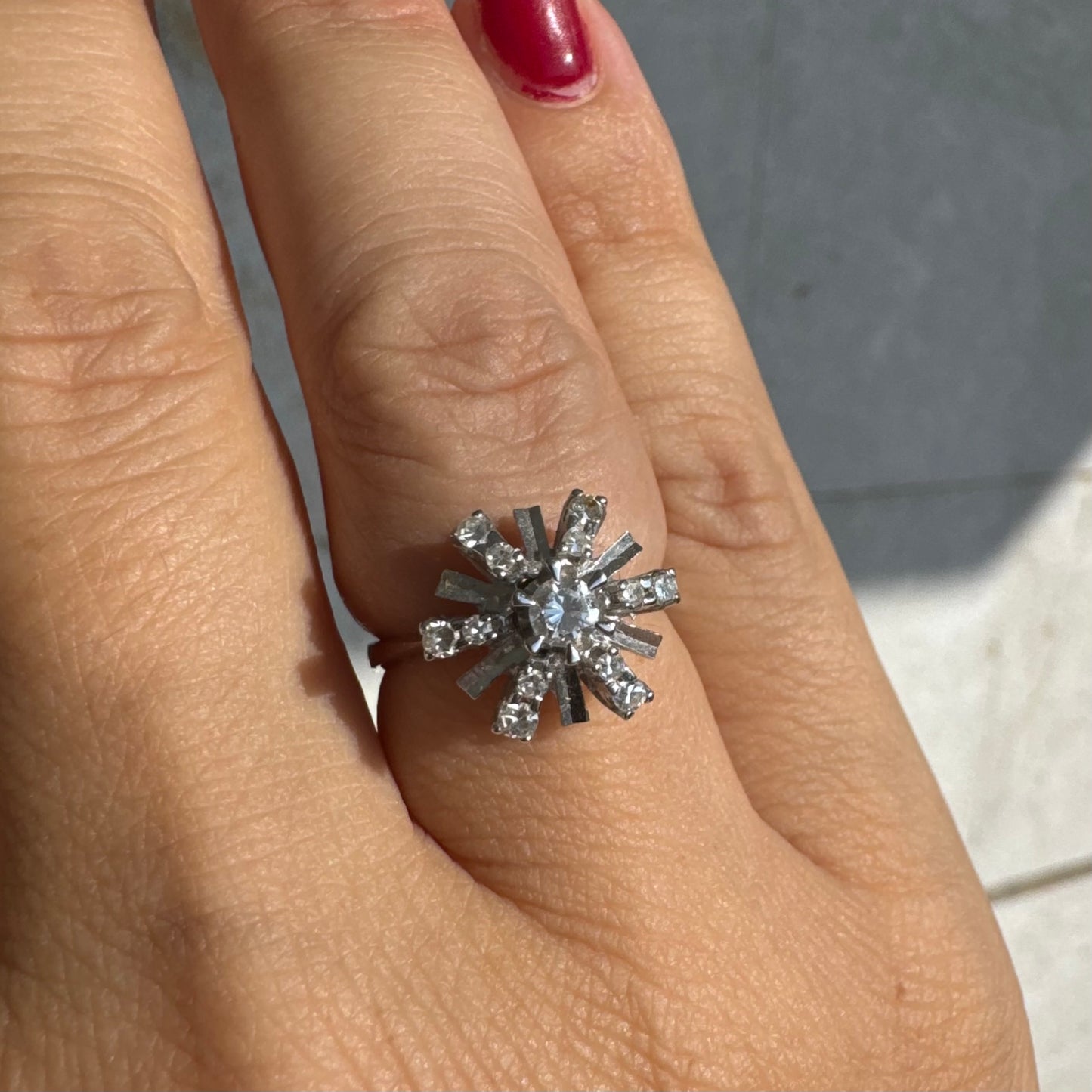 טבעת זהב לבן 18 קראט בעיצוב קרני שמש מרהיב, משובצת יהלומים הלוכדים את האור מכל כיוון. 