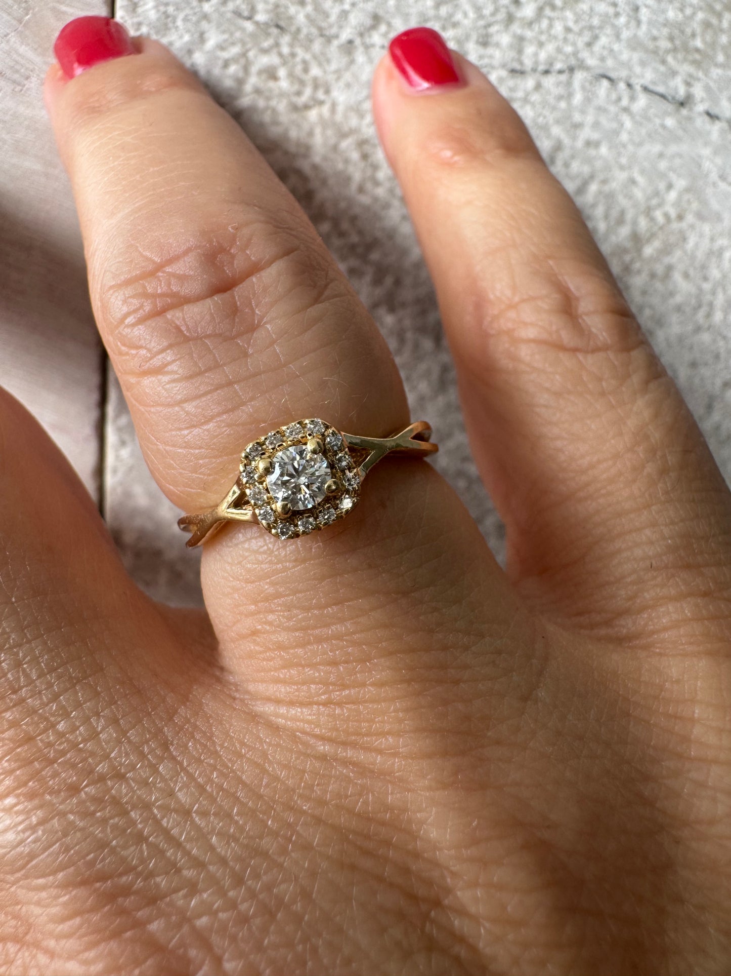 טבעת זהב 14 קראט משובצת יהלום מרכזי עגול ומבריק, מוקף הילה עדינה של יהלומים המעצימים את הברק