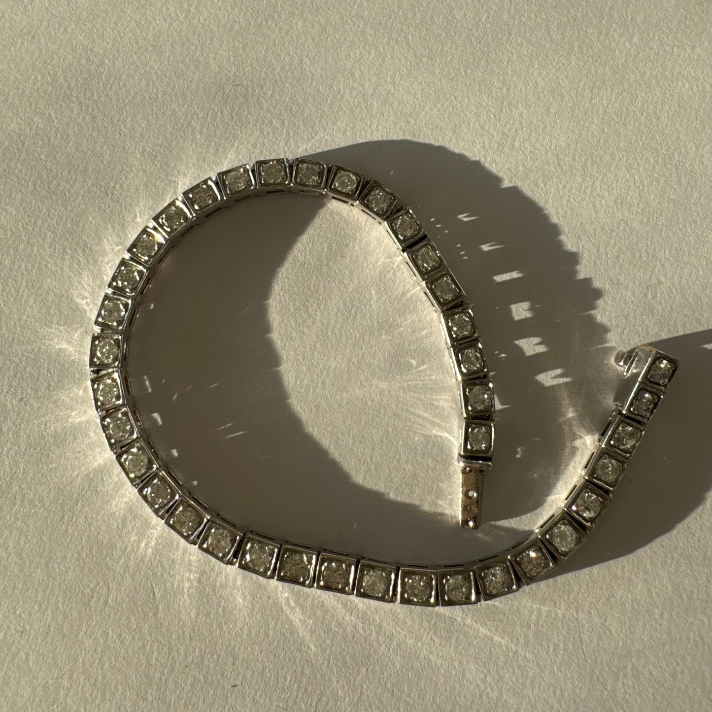 צמיד טניס זהב לבן 18 קראט משובץ יהלומים עגולים נוצצים בתוך מסגרות ריבועיות.