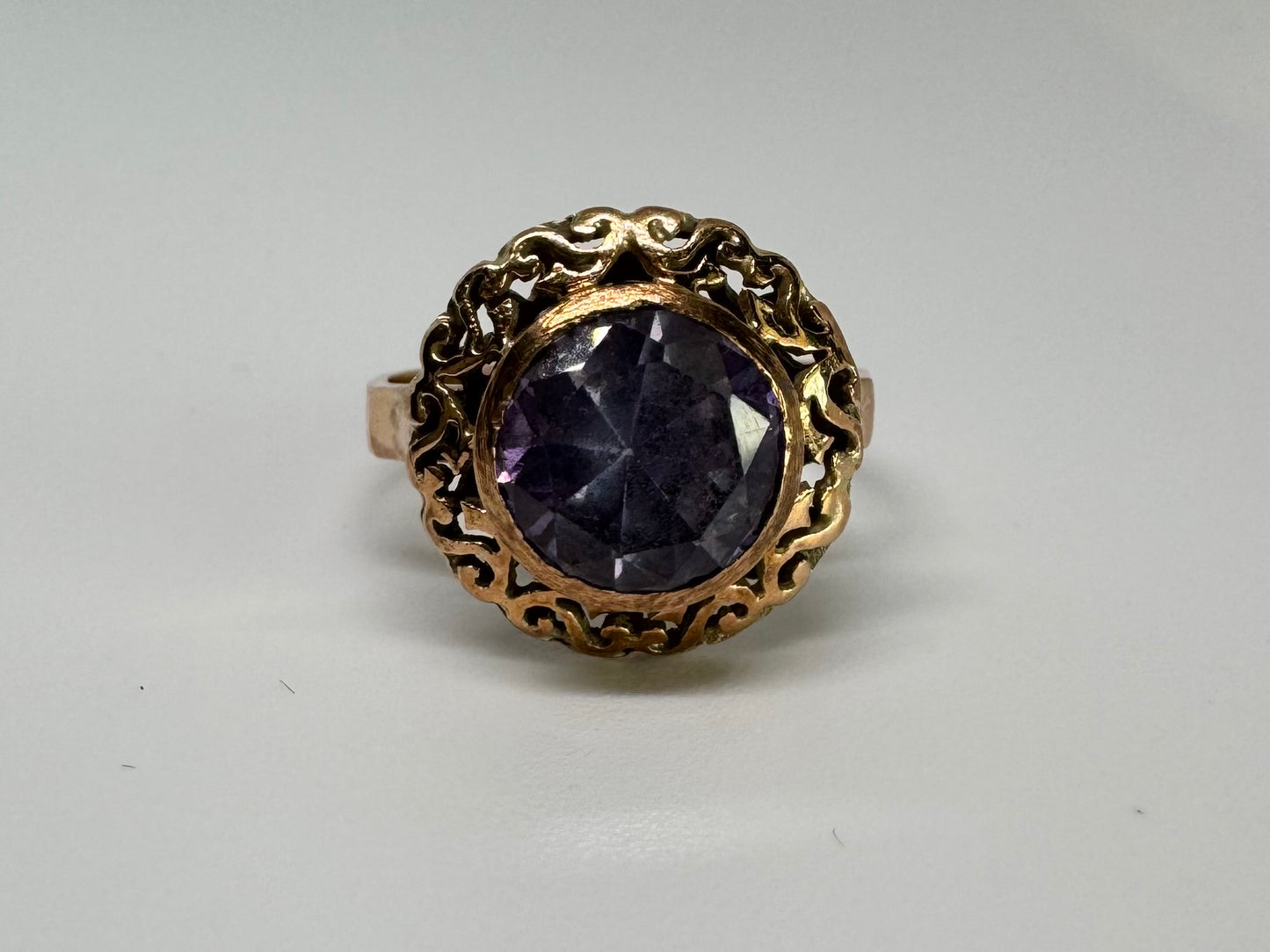 14K gold ring set with a large round-cut Tanzanite framed by an ornate filigree bezel