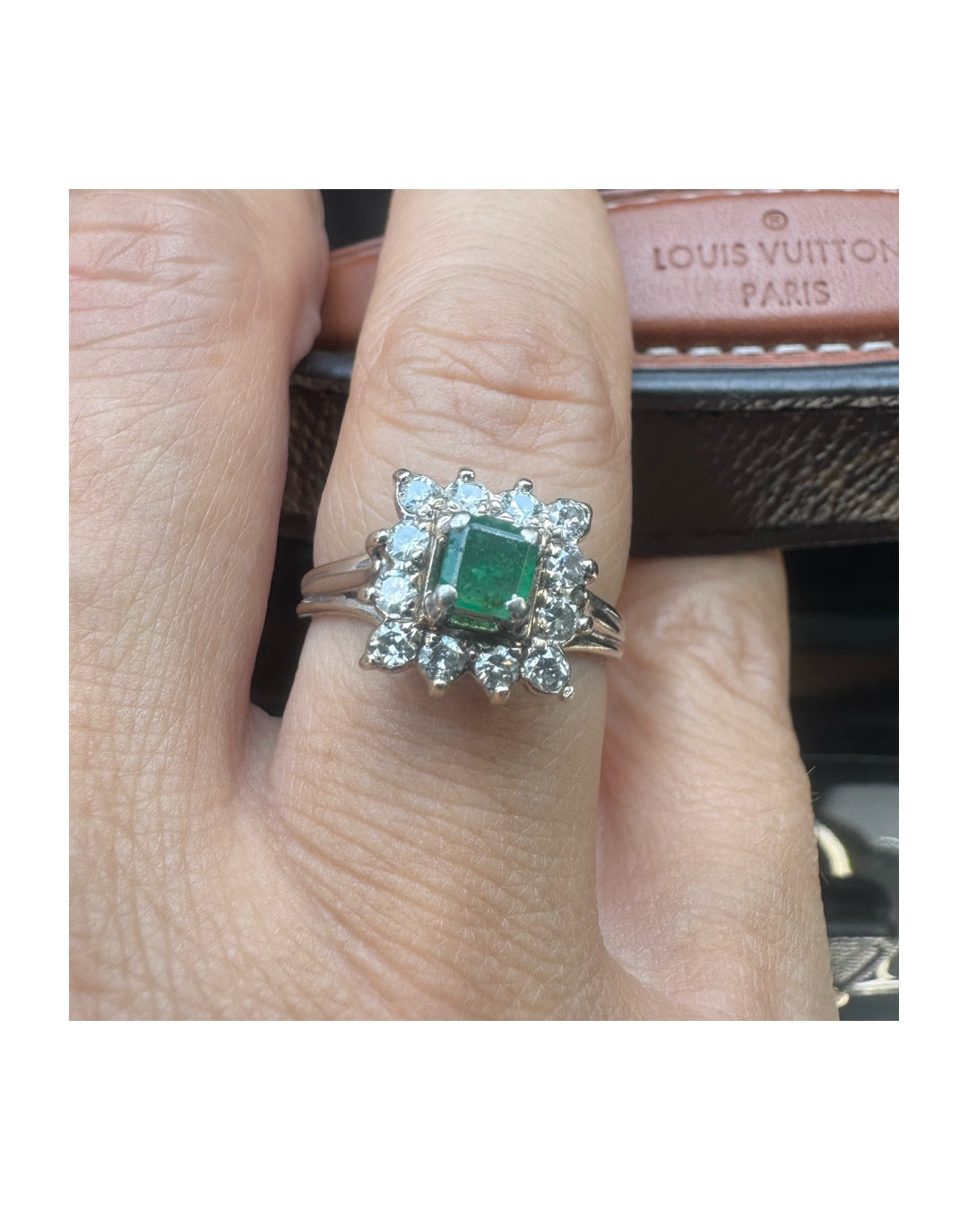 טבעת זהב לבן 18 קראט משובצת אבן אמרלד  מרובעת במרכז, מוקפת בהילה נוצצת של יהלומים.