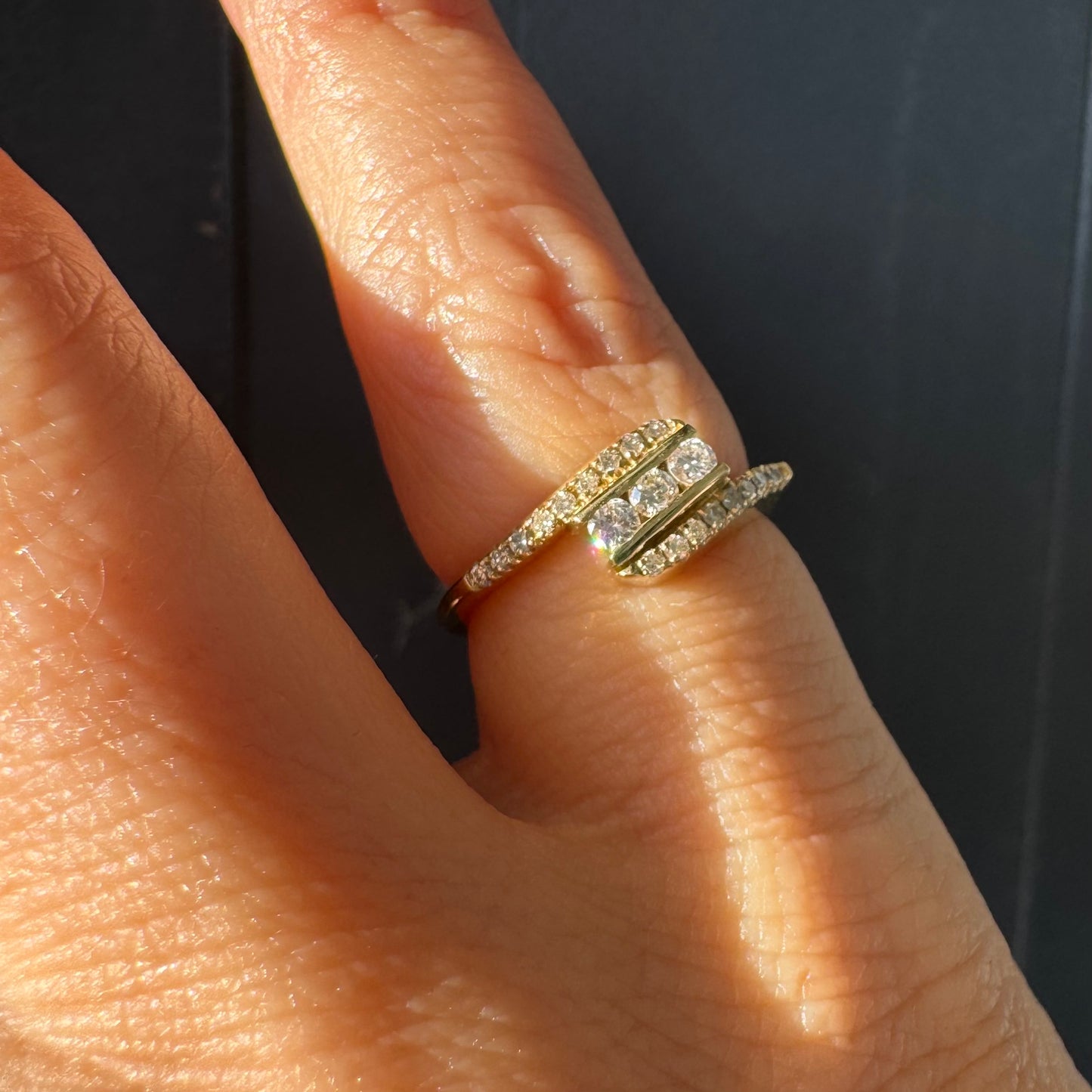 טבעת זהב צהוב 14 קראט בעיצוב ייחודי, משובצת שלושה יהלומים מרכזיים ושורות נוספות של יהלומים לאורך הזרועות. 