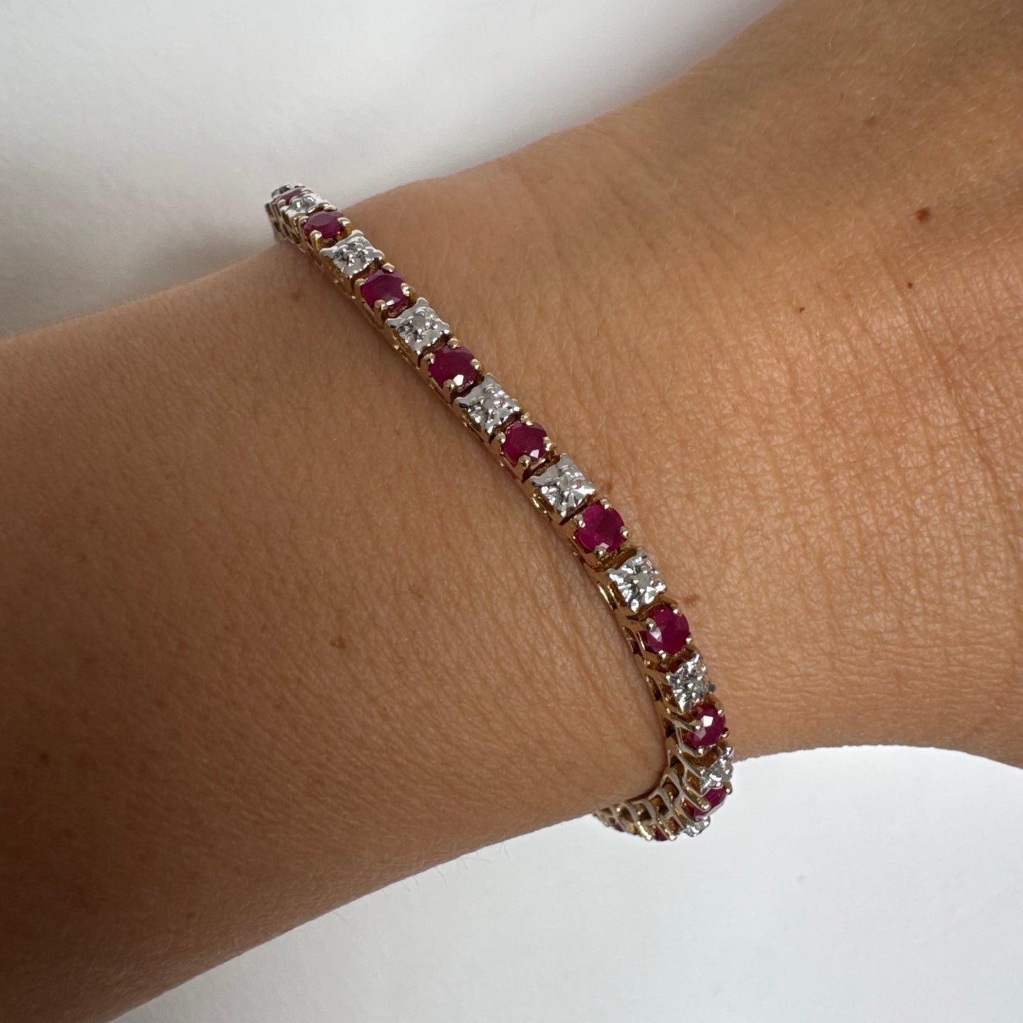 צמיד זהב צהוב 10 קראט משובץ אבני רובי בגוון אדום עמוק וביניהן יהלומים לבנים מנצנצים.