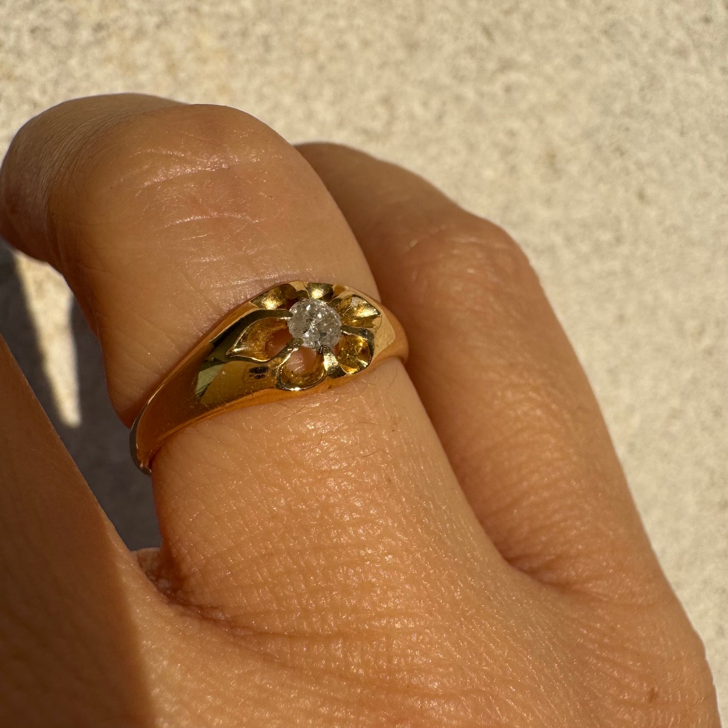 טבעת זהב צהוב 18 קראט בעיצוב פרח עדין, משובצת יהלום מרכזי בתוך עלי כותרת פתוחים.