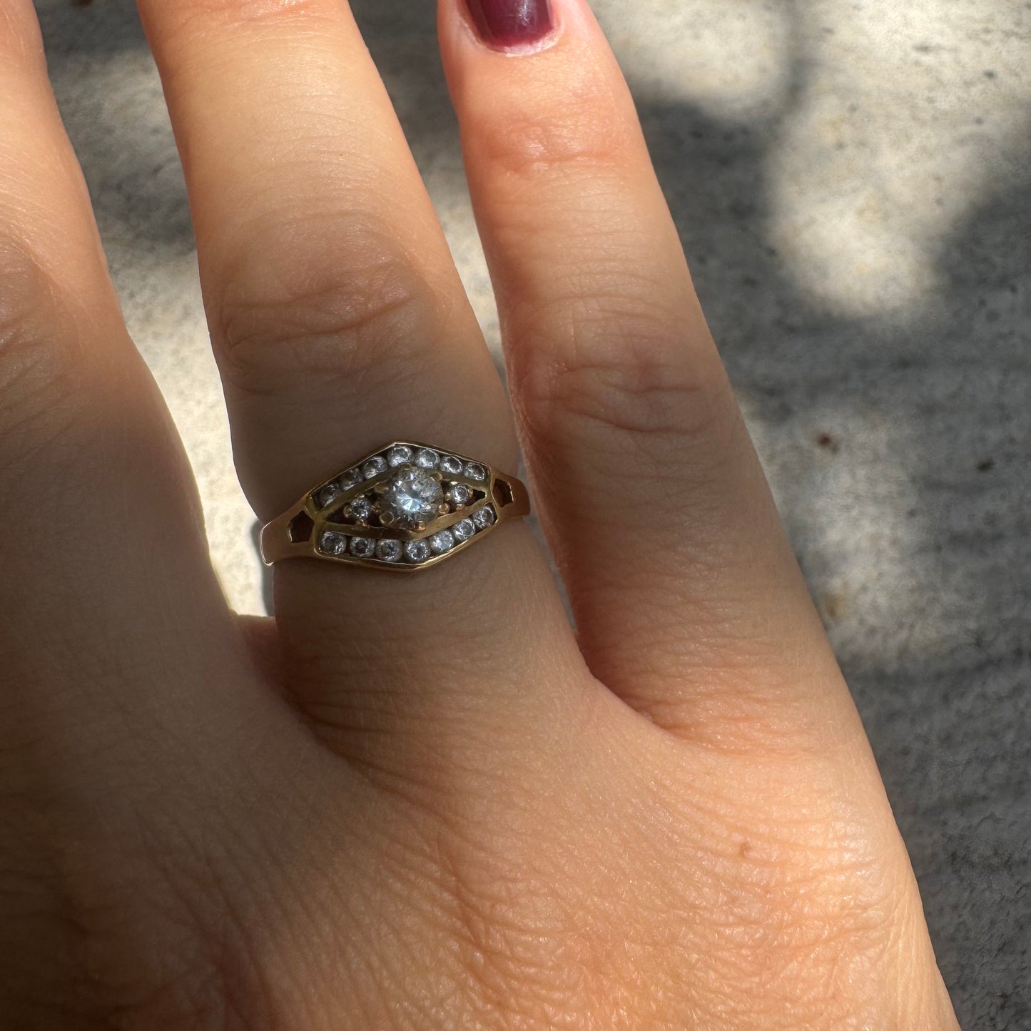 18K gold ring set with a central round Diamond, surrounded by rows of Diamonds in a decorative setting.