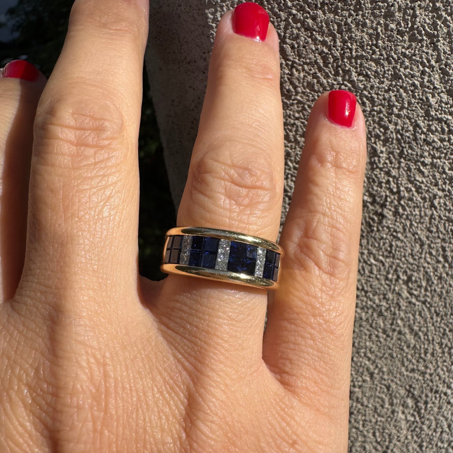 טבעת ה.שטרן זהב צהוב 18 קראט, בעיצוב רחב ומרשים. משובצת שורת אבני ספיר כחולות מרובעות בשילוב מחיצות של יהלומים לנגיעת ברק יוקרתי.
