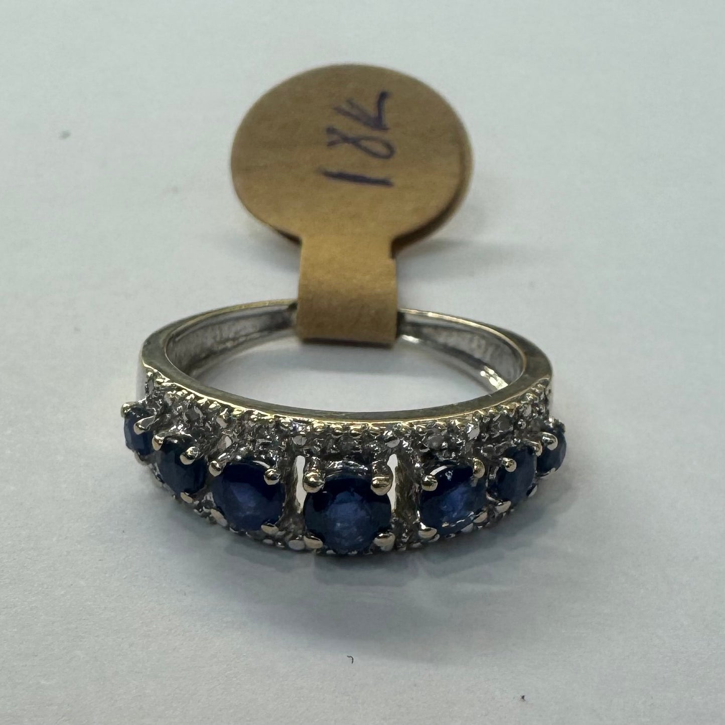 18K gold ring set with deep blue sapphires in a classic round cut, framed by two shimmering rows of brilliant Diamonds.