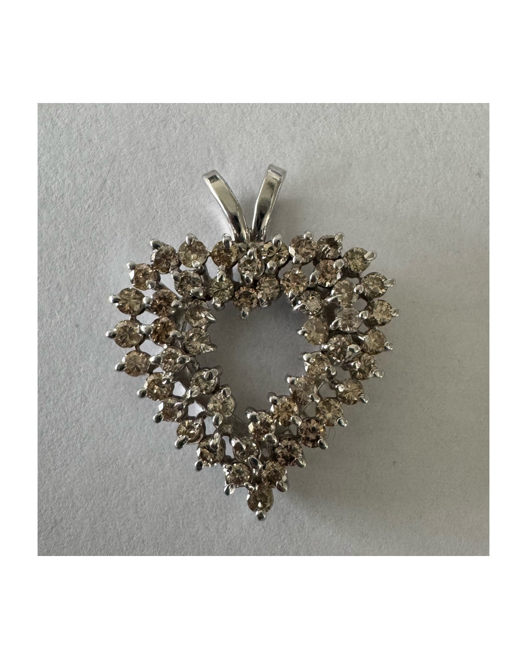 תליון לב זהב לבן 14 קראט, משובץ יהלומים בשיבוץ שיניים עדין היוצר מראה עשיר ומלא ברק.