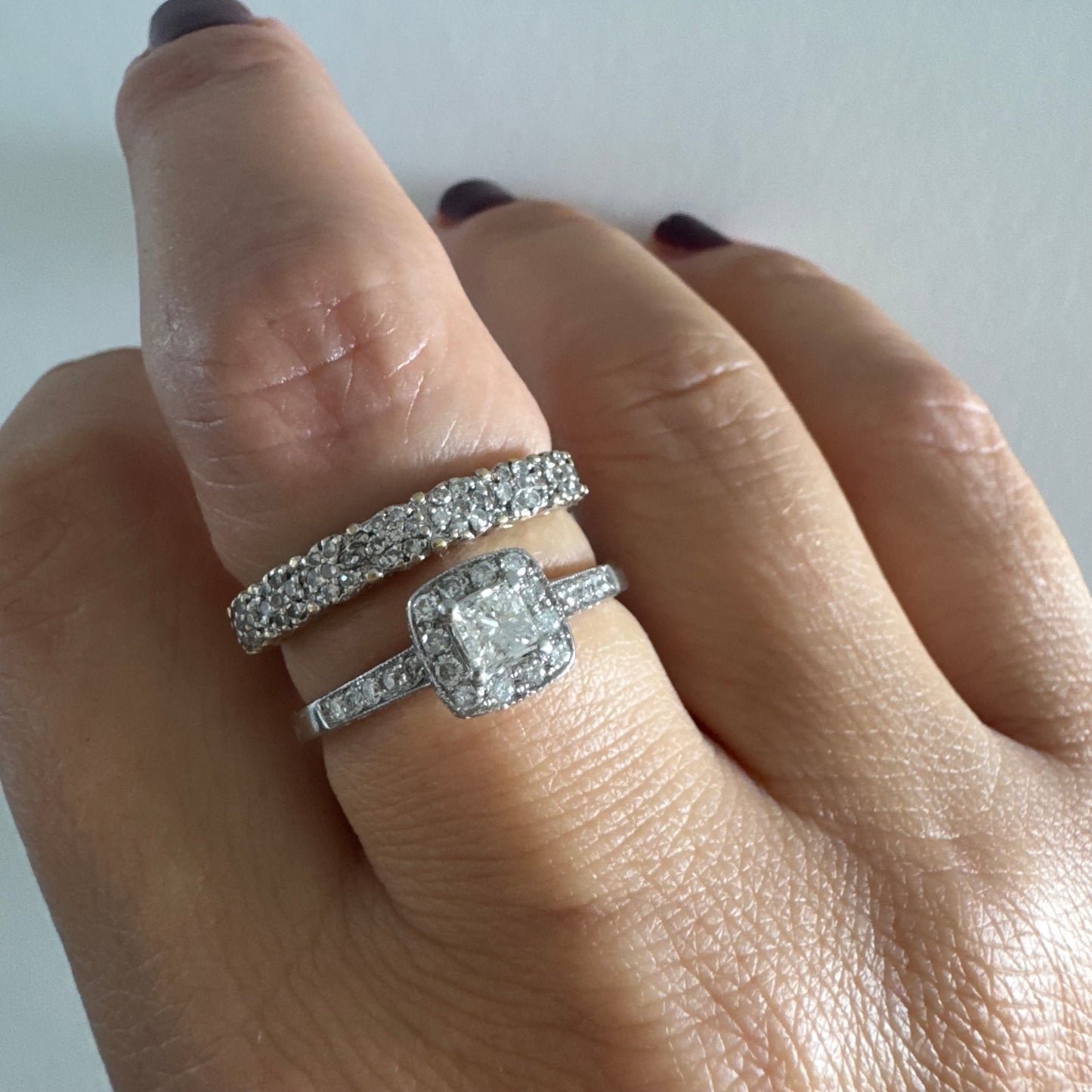 טבעת זהב לבן 14 קראט משובצת יהלום מרכזי בחיתוך פרינסס, מוקף הילת יהלומים קטנים וזרוע משובצת פאווה