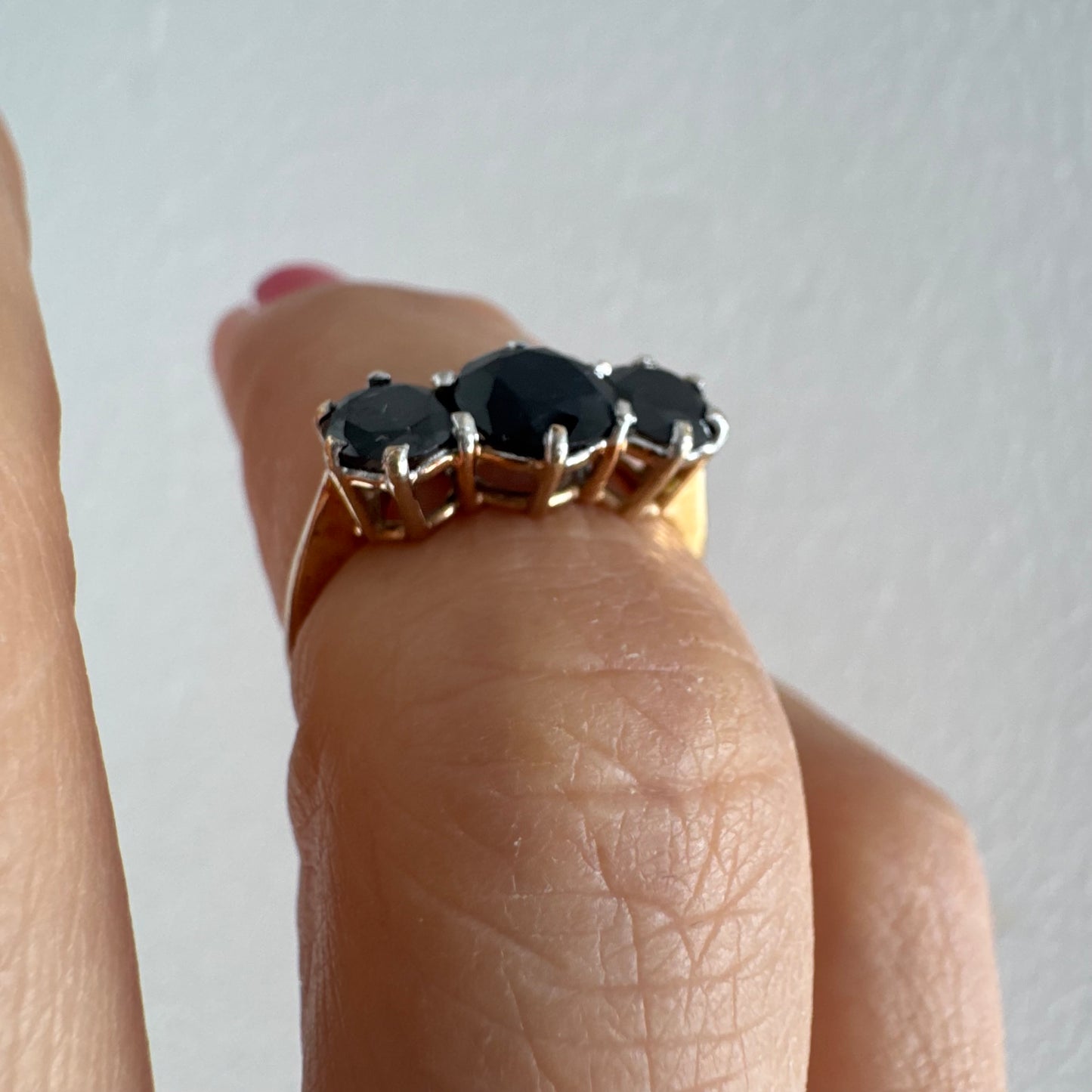 טבעת זהב 10 קראט משובצת שלוש אבני ספיר בצבע כחול כהה בחיתוך עגול, בעיצוב קלאסי עם נוכחות עמוקה ואלגנטית.