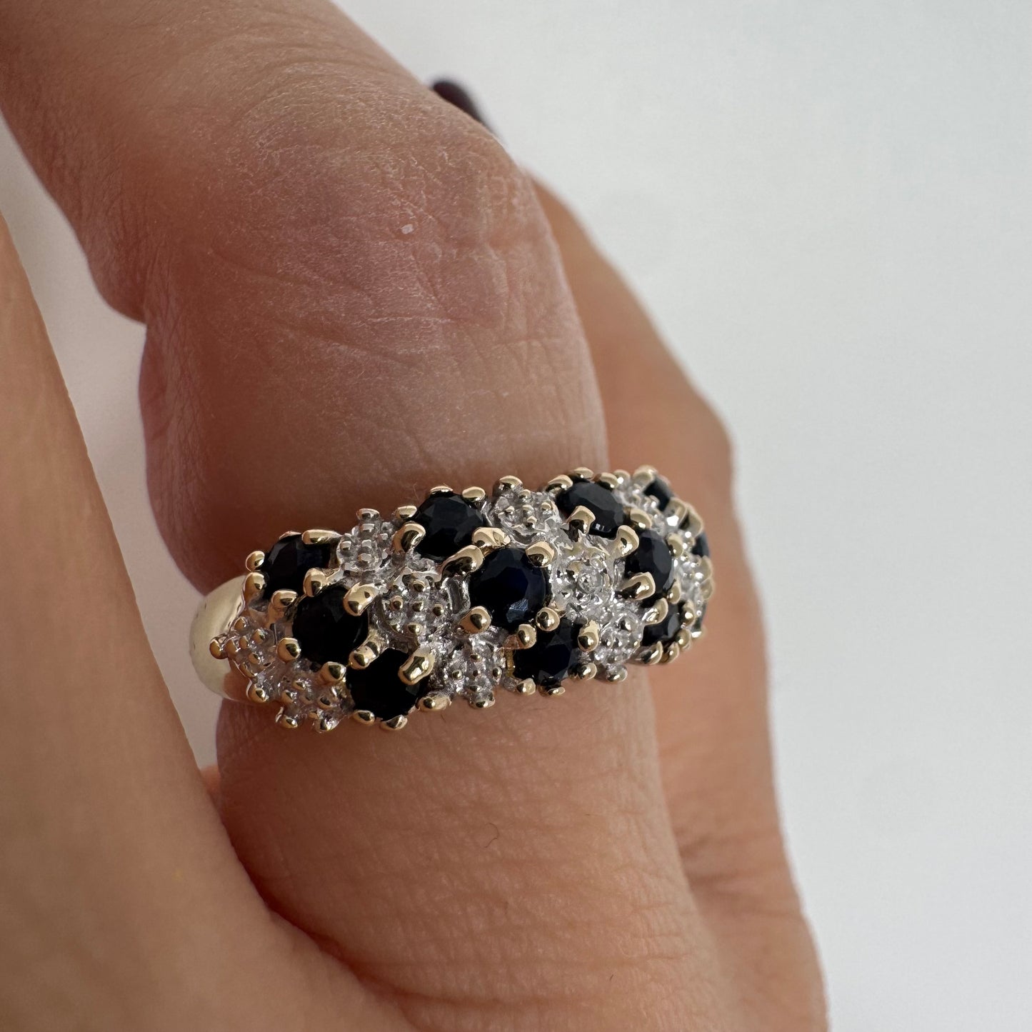 טבעת זהב צהוב 10 קראט משובצת אבני ספיר כהות ויהלומים בעיצוב קלאסי ורומנטי.