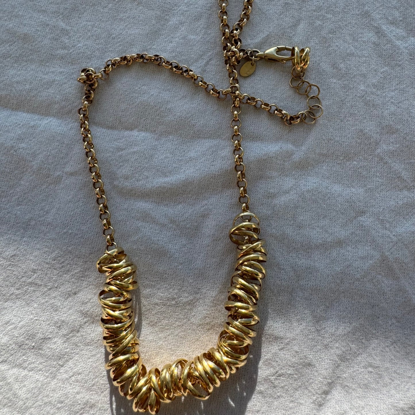 14K gold necklace featuring a series of intertwined gold rings creating a bold and sculptural design.