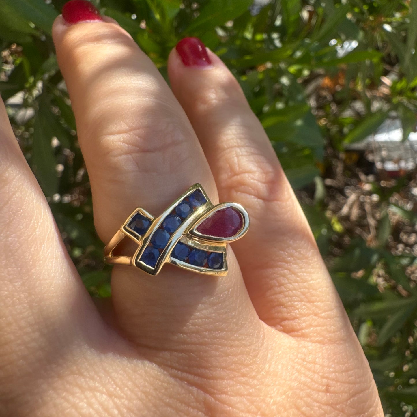 10K gold ring set with a pear-shaped Ruby and deep blue Sapphires in a geometric design.