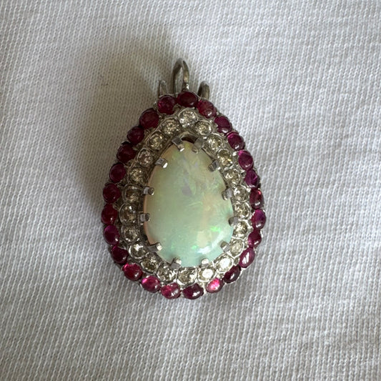 תליון זהב 14 קראט משובץ אבן אופל בחיתוך טיפה, מוקפת בשתי מסגרות של יהלומים ורובי נוצצים. 