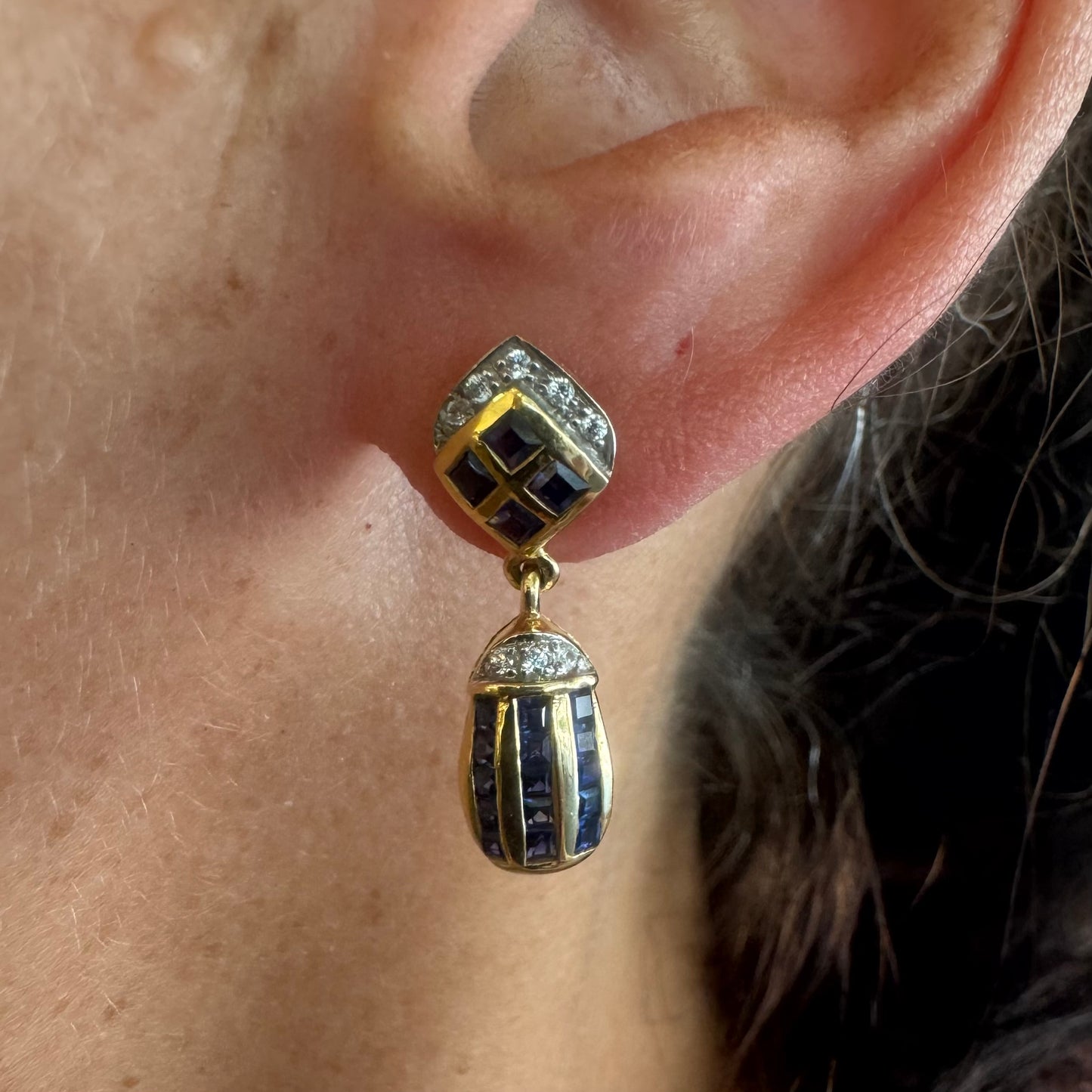 עגילי זהב צהוב 18 קראט תלויים, משובצים אבני ספיר כחולות בגוון כחול עמוק בעיצוב גיאומטרי, בשילוב יהלומים מנצנצים