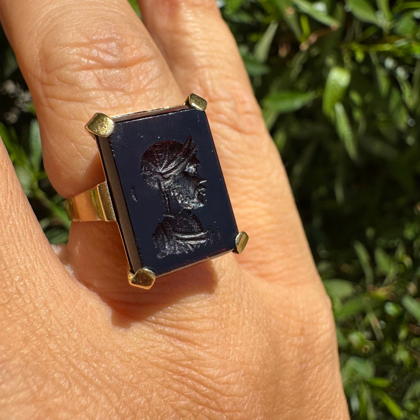 18K gold ring set with a carved dark stone featuring a classical warrior profile.