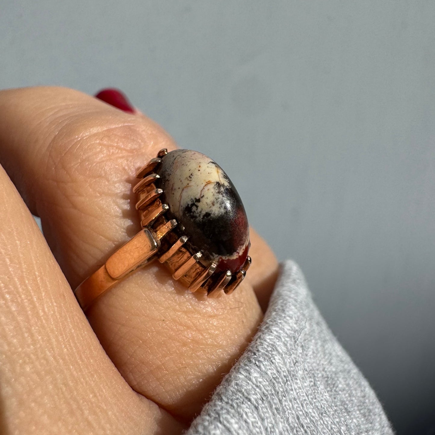 טבעת זהב 14 קראט משובצת אבן ג’ספר ייחודית בגווני קרם, שחור ואדום. 