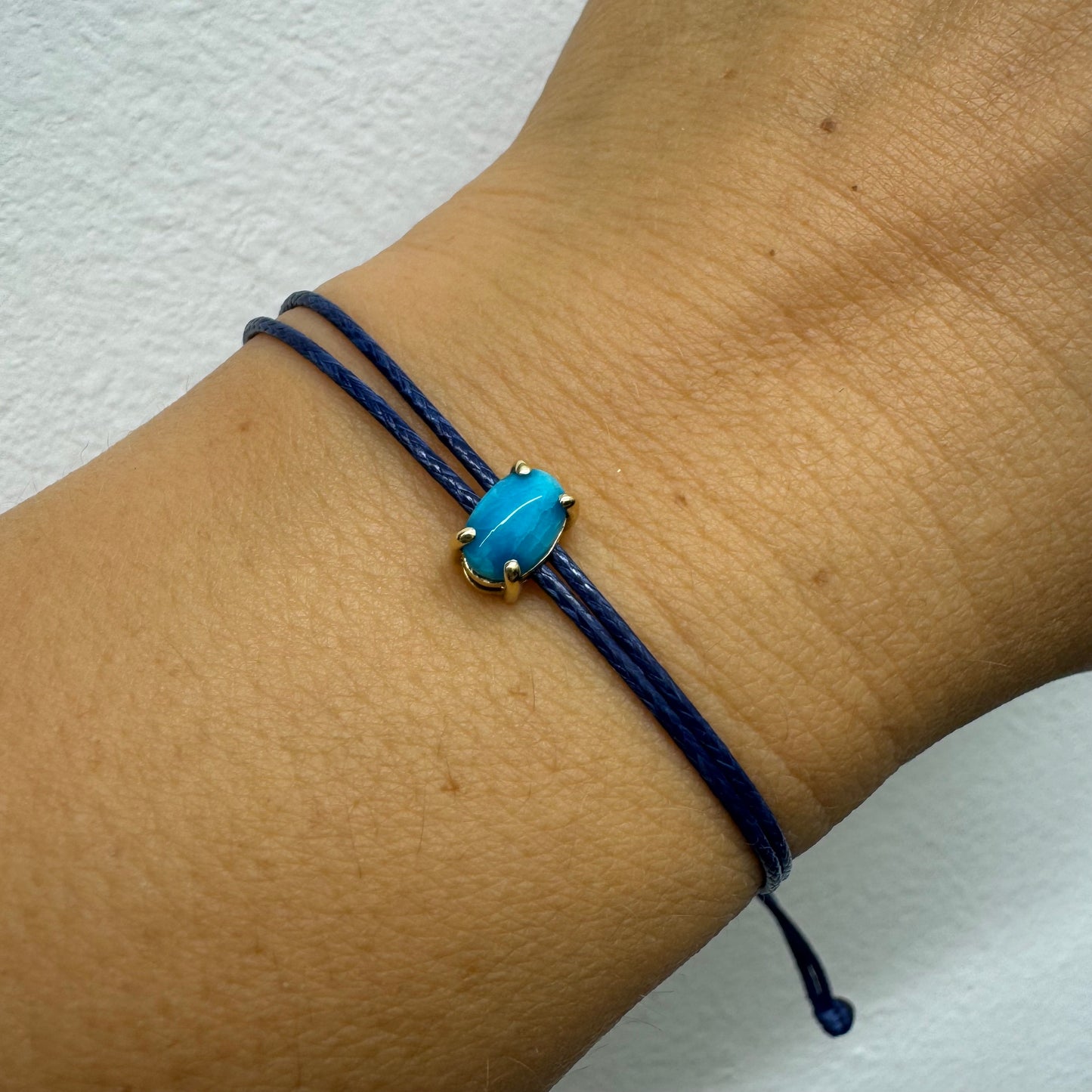 צמיד חוט כחול עדין עם אבן טורקיז טבעית בגוון כחול עמוק, משובצת במסגרת זהב.