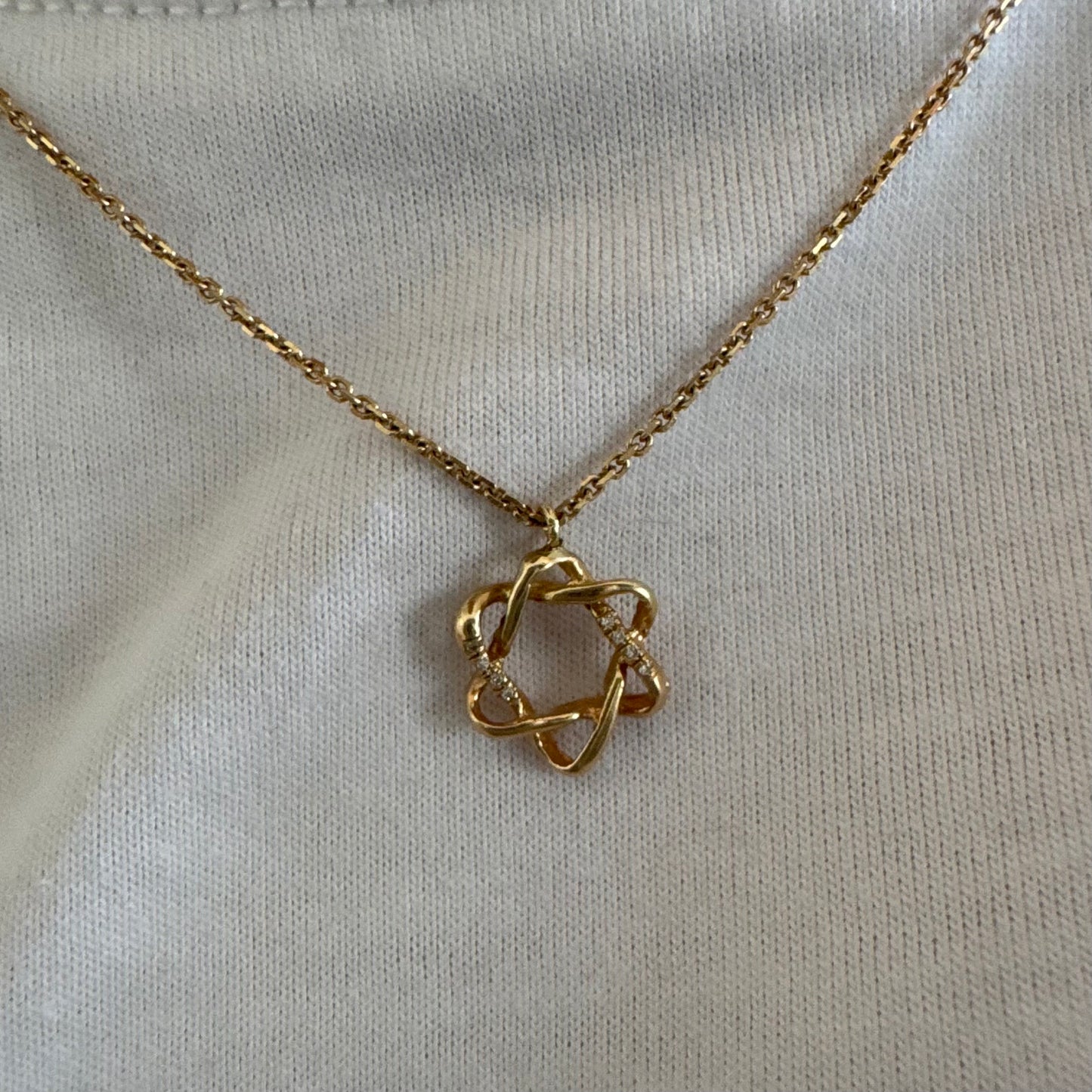 תליון ״מגן דוד״ זהב 14 קראט בעיצוב פתוח ופיסולי, המורכב מקווים זורמים המשתלבים זה בזה ליצירת צורה הרמונית וייחודית.