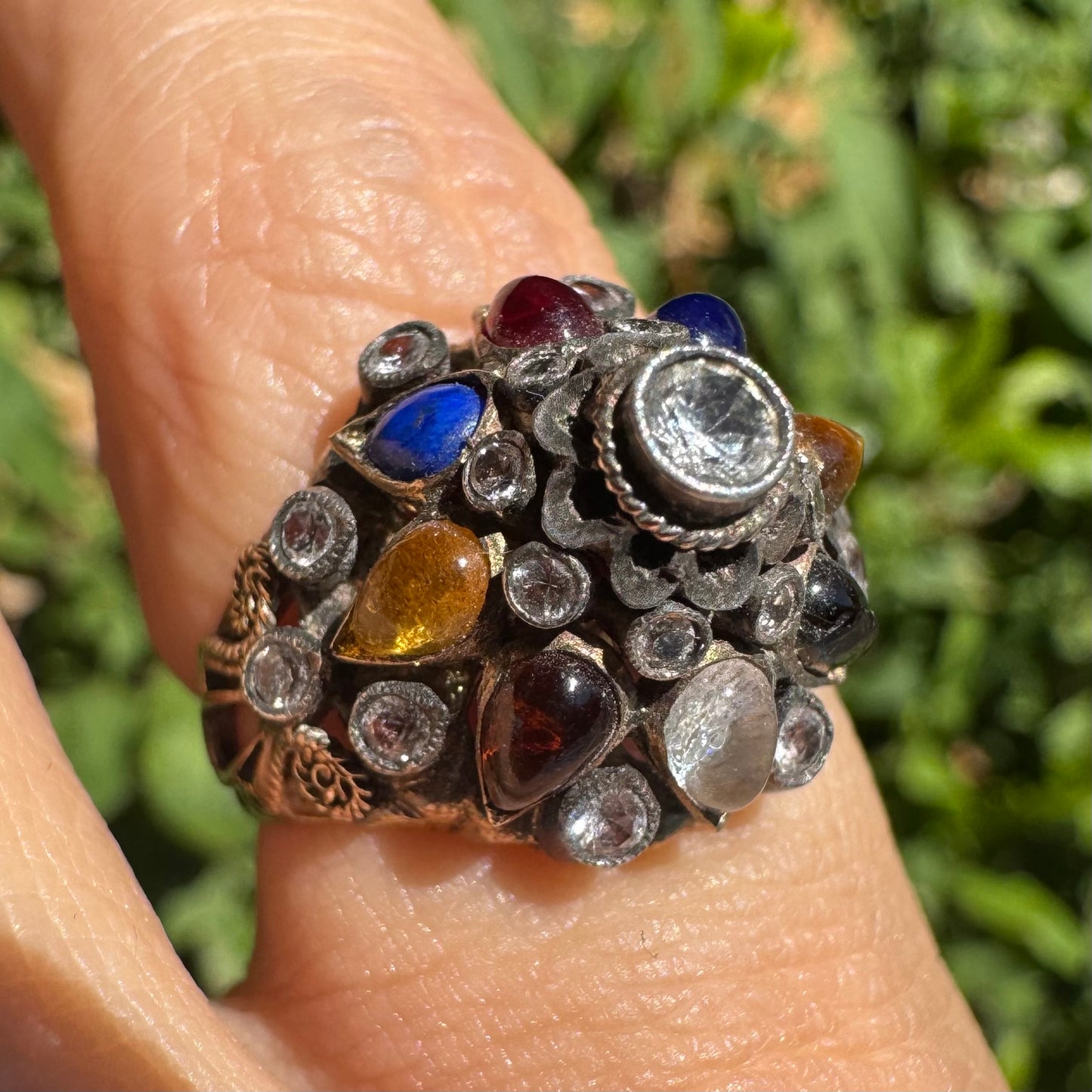 טבעת זהב צהוב 14 קראט משובצת אבן מרכזית שקופה וסביבה פסיפס צבעוני של אבני חן צבעוניות: גרנט, עין הנמר, ואבני חן נוספות, בשיבוץ ידני בסגנון עתיק