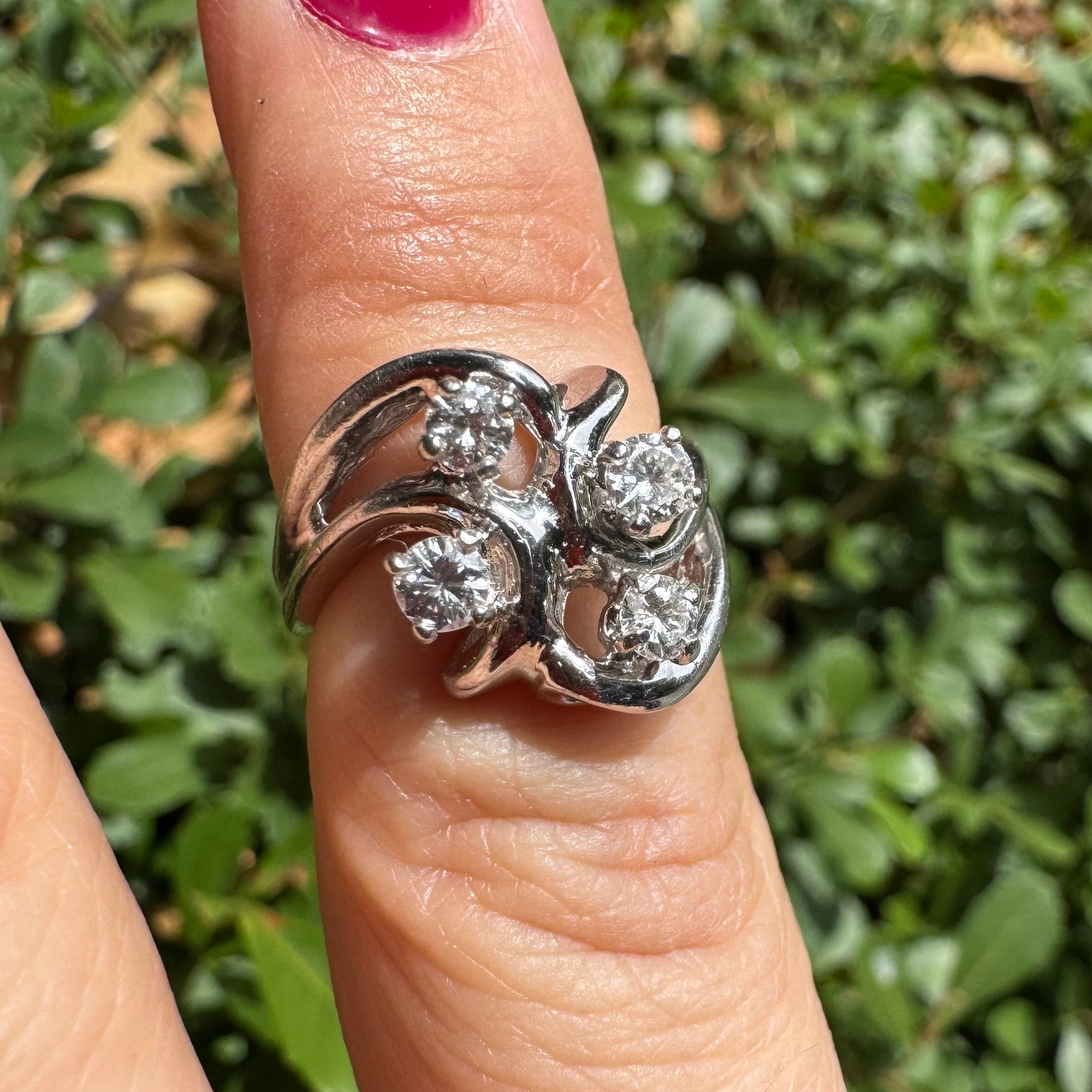 טבעת זהב לבן 14 קראט בעיצוב מודרני-פיסולי, משובצת בארבעה יהלומים נוצצים בשיבוץ חופשי המדמה תנועה אלגנטית של עלים.