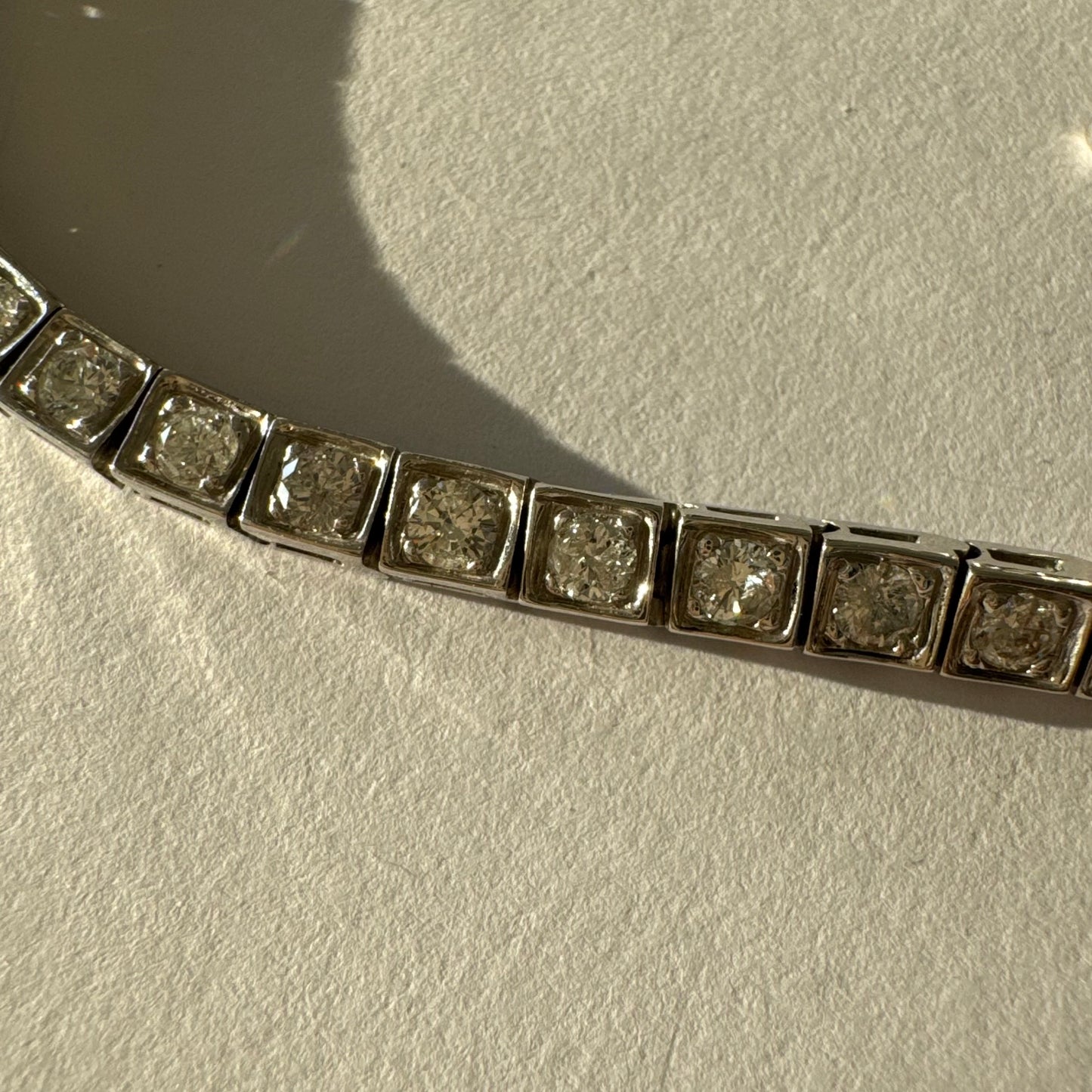 צמיד טניס זהב לבן 18 קראט משובץ יהלומים עגולים נוצצים בתוך מסגרות ריבועיות.