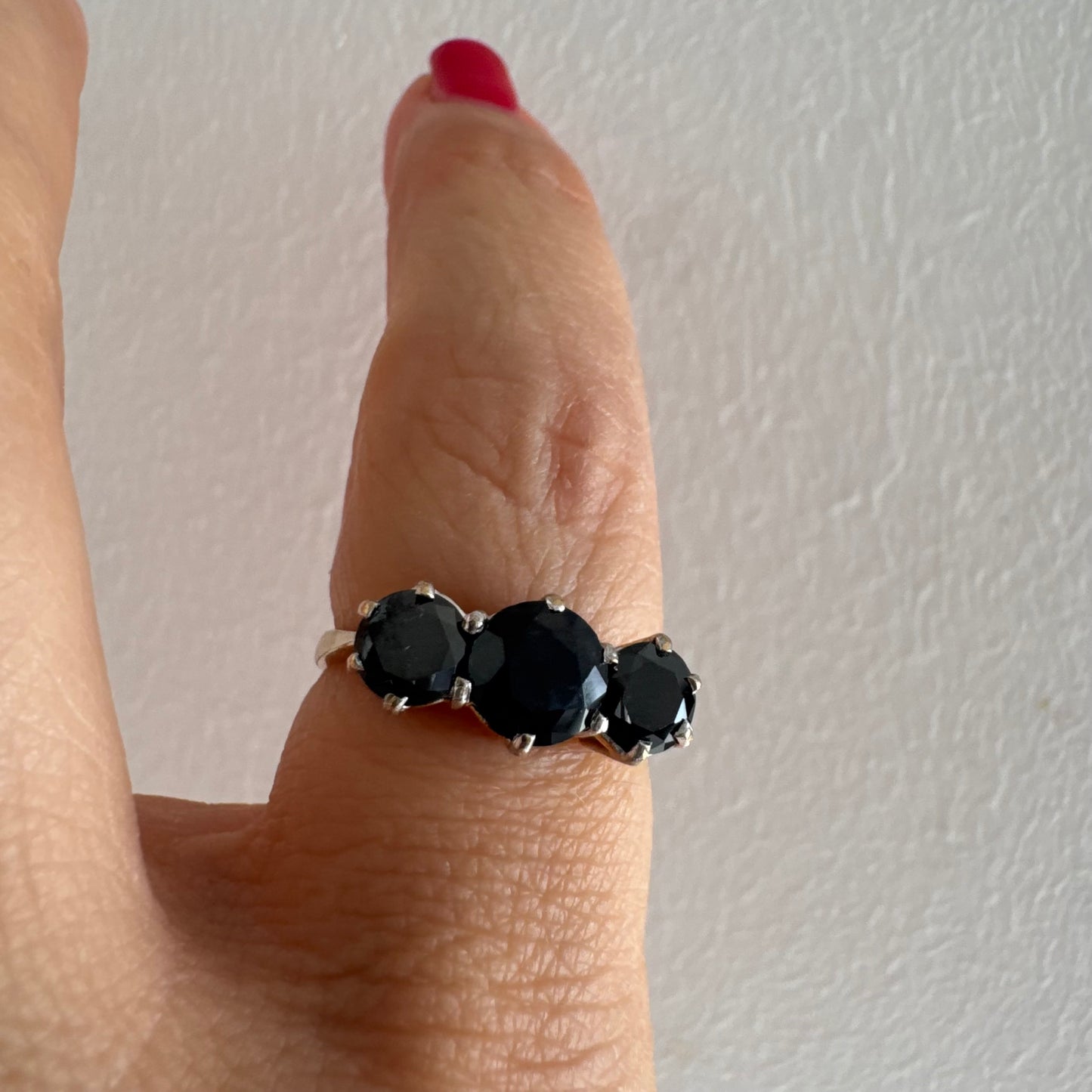 טבעת זהב 10 קראט משובצת שלוש אבני ספיר בצבע כחול כהה בחיתוך עגול, בעיצוב קלאסי עם נוכחות עמוקה ואלגנטית.