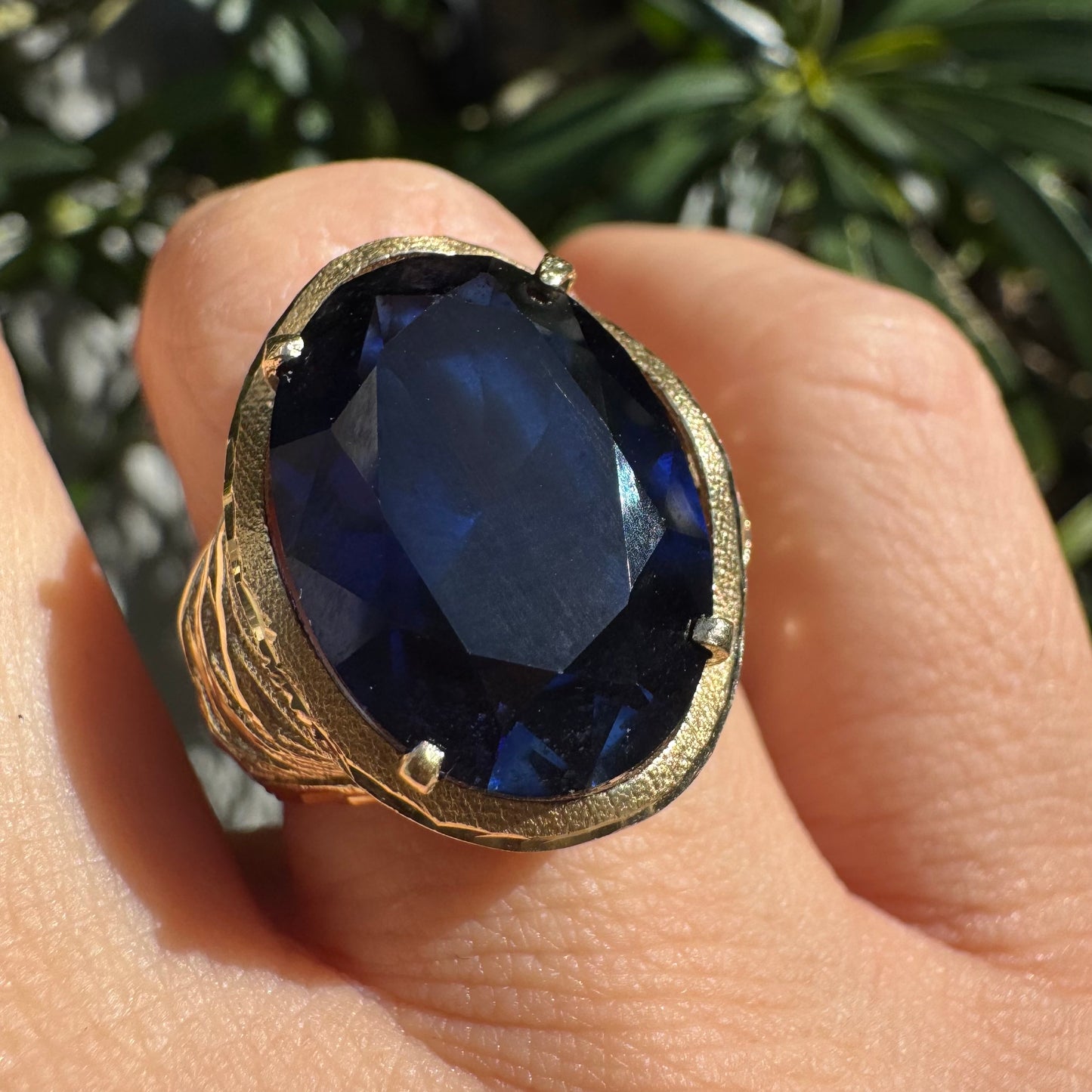 14K gold ring set with a deep navy-blue oval Sapphire in a dramatic openwork setting