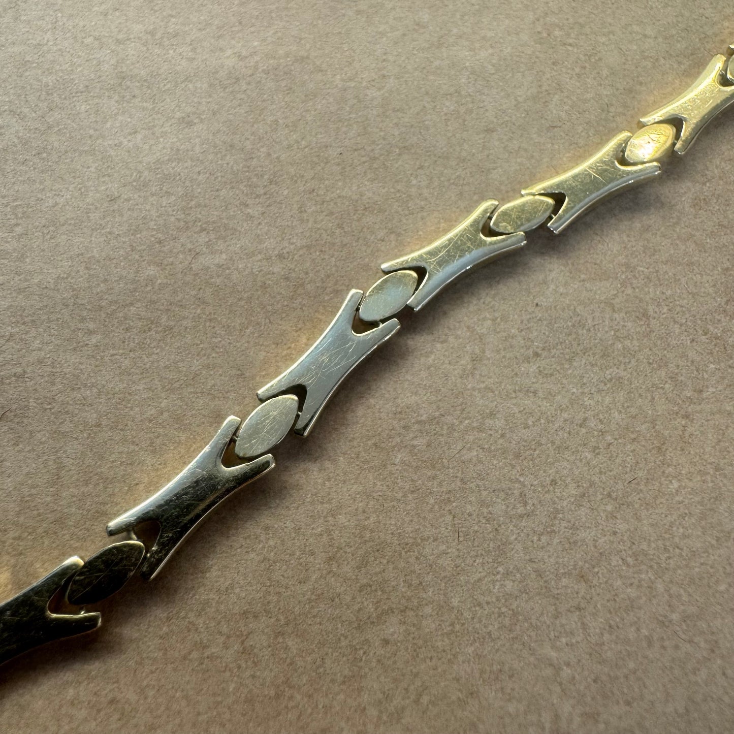 צמיד זהב צהוב וזהב לבן 14 קראט בעיצוב גאומטרי מיוחד, עם חיבורים בצורת X מזהב צהוב ושיבוצים מבריקים בזהב לבן