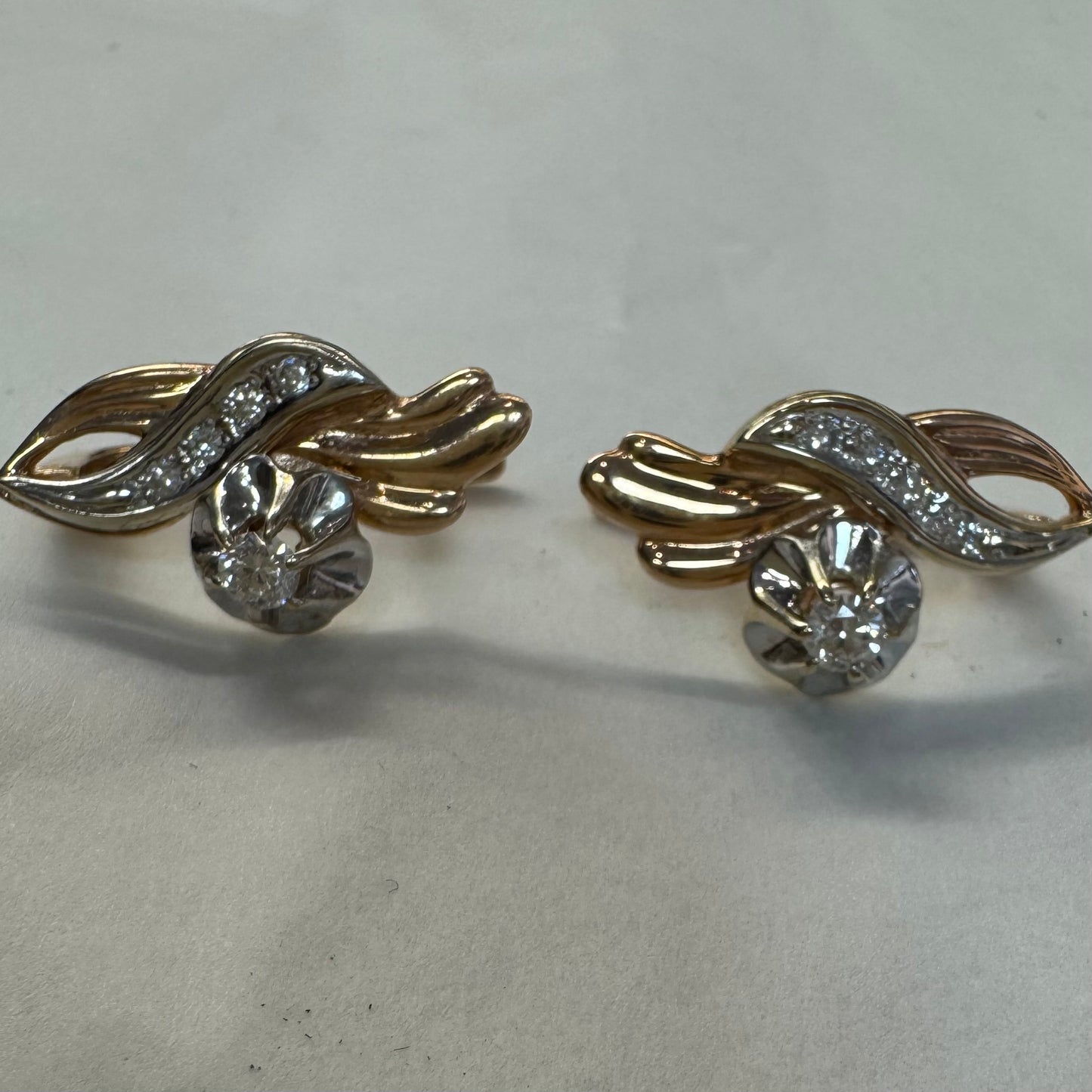 עגילי זהב 14 קראט בעיצוב מתעגל ואלגנטי המשובצים יהלומים נוצצים .