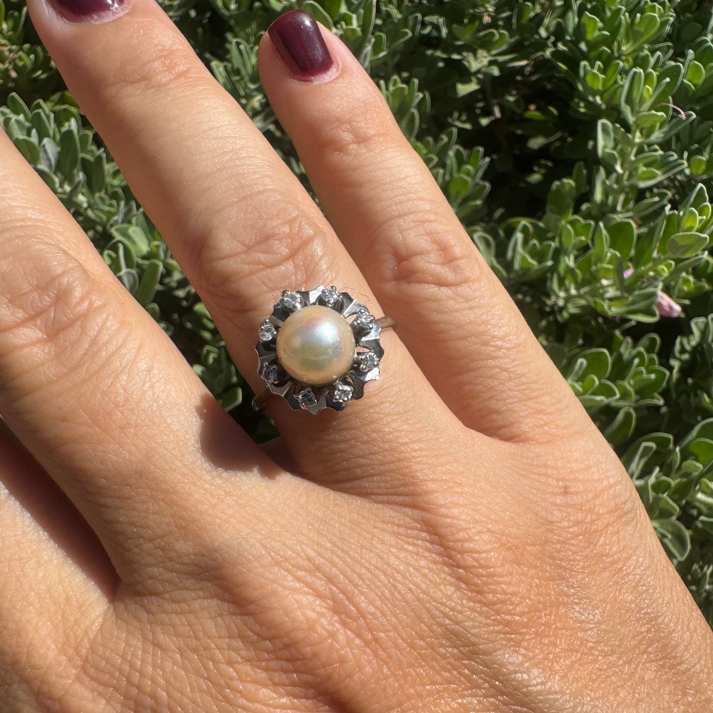 18K gold ring set with a round Pearl at the center, surrounded by a floral halo set with small Diamonds.