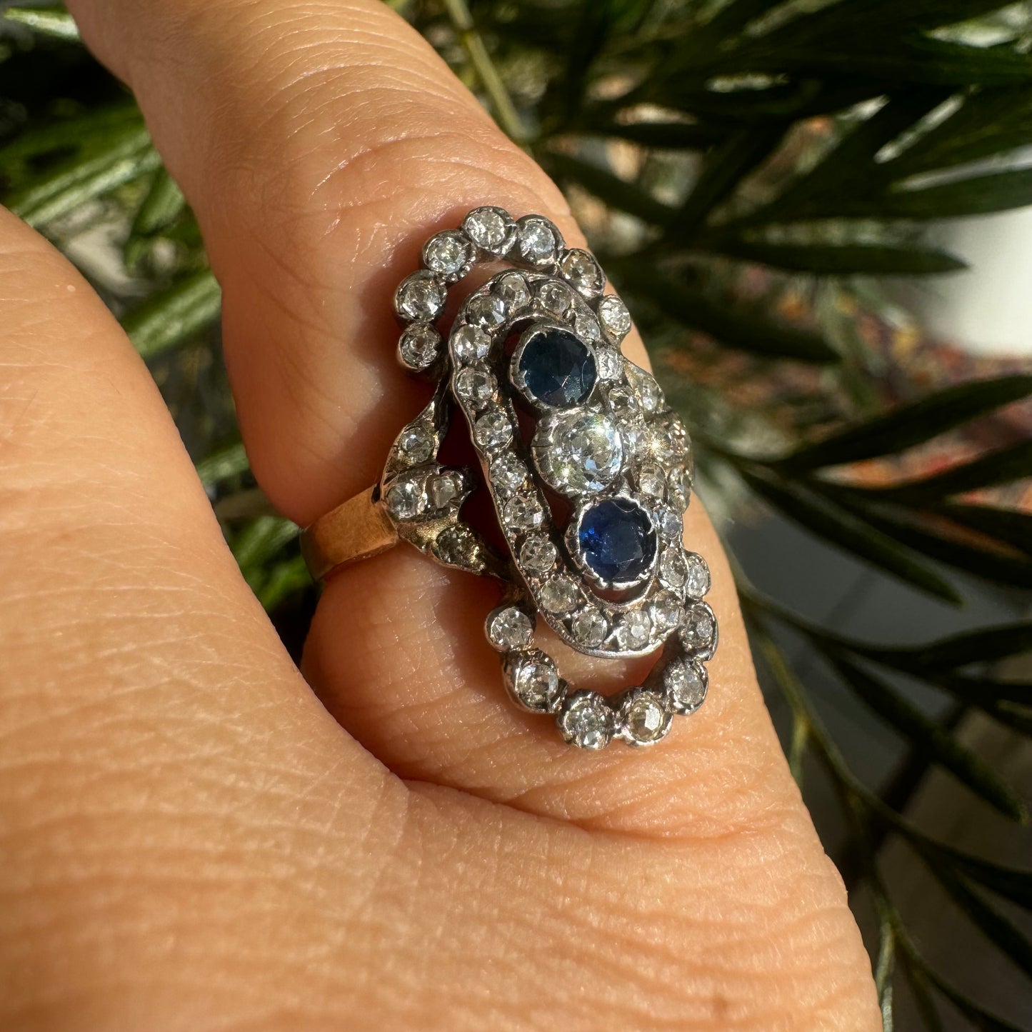 14K gold Antique featuring a stunning trio of gemstones - two deep blue Sapphires surrounding a brilliant old-cut Diamonds