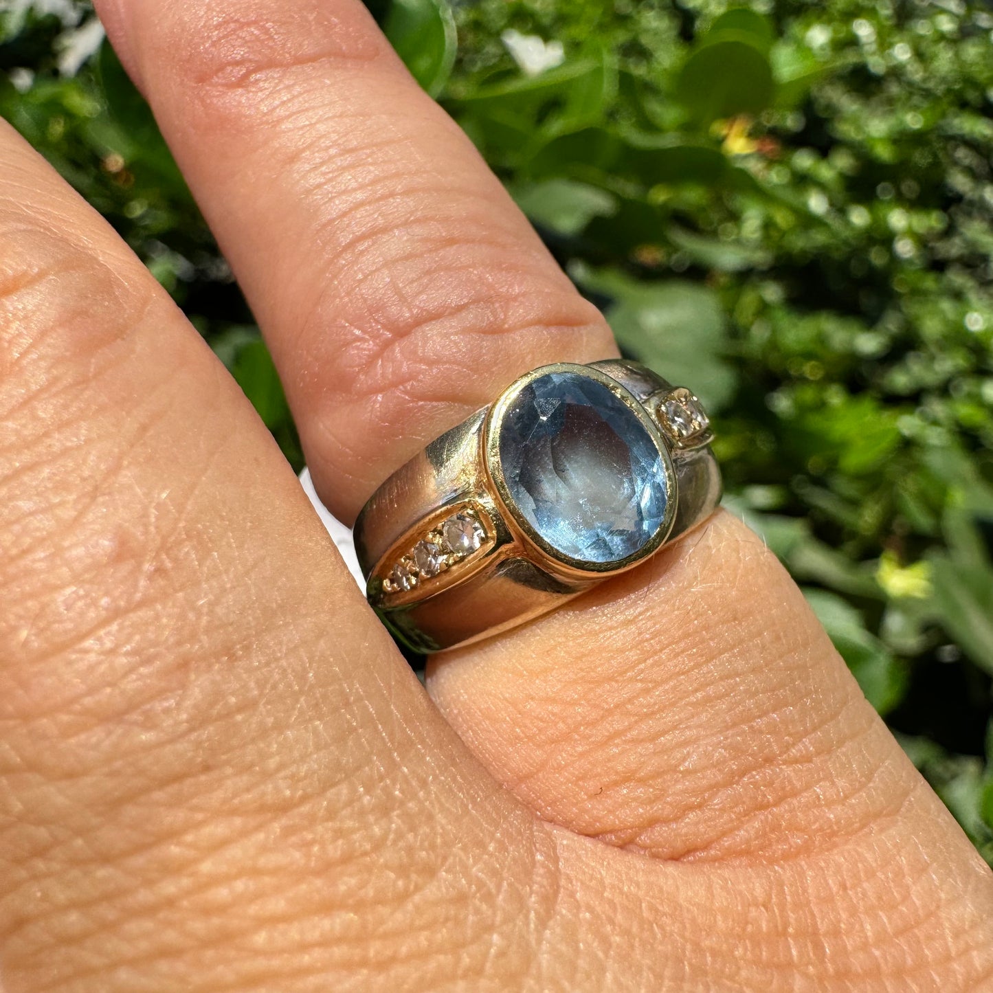 14K gold ring set with a luminous Blue Topaz at its center, accented by delicate side Diamonds