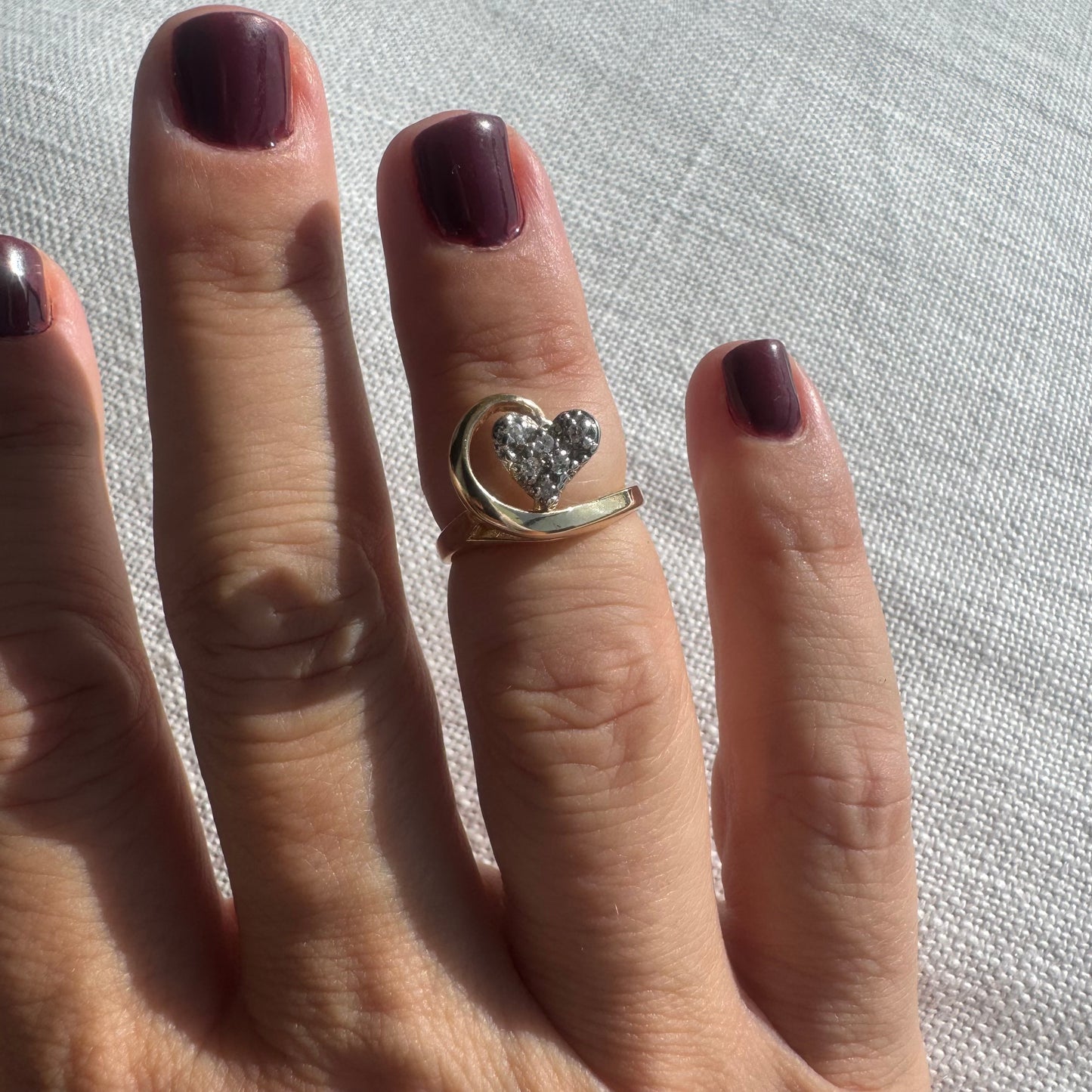 14K gold ring featuring a Diamond-studded heart embraced by a flowing golden curve.