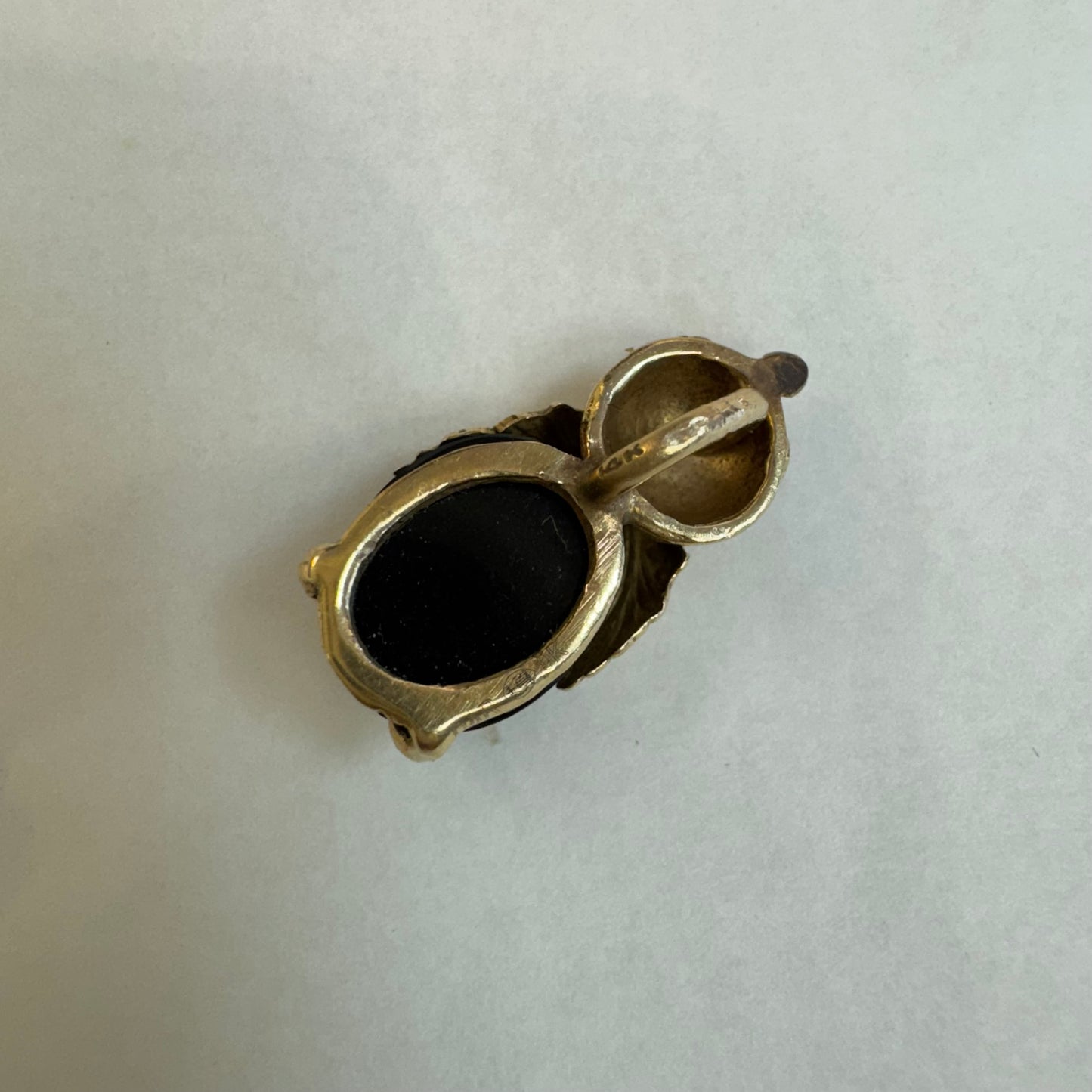 תליון בצורת חיפושית מזהב 14 קראט, עם עיניים אדומות מאבן קורל בחיתוך קבושון וגוף מאבן אוניקס שחורה מבריקה.