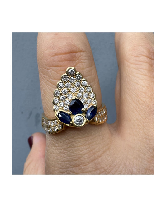 טבעת זהב צהוב 18 קראט משובצת יהלומים ואבני ספיר כחולות, בעיצוב יוקרתי ומלא נוכחות.