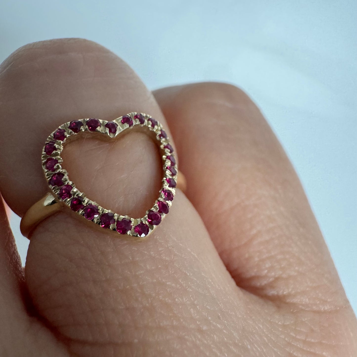 14K yellow gold open-heart ring set with deep red rubies along the frame.