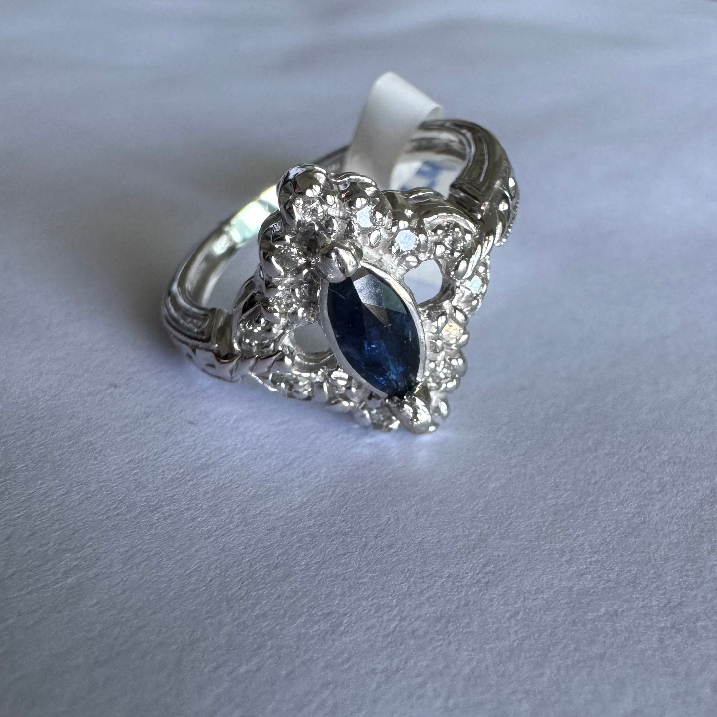טבעת זהב לבן 14 קראט משובצת אבן ספיר בצבע כחול כהה בחיתוך מרקיזה ומסביב משובצים יהלומים