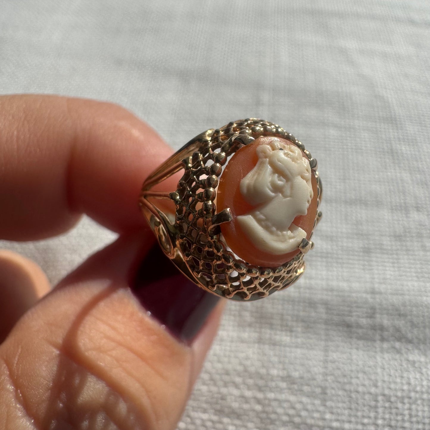18K gold ring featuring a hand-carved Cameo of a delicate female profile in ivory tones on a warm Coral background.