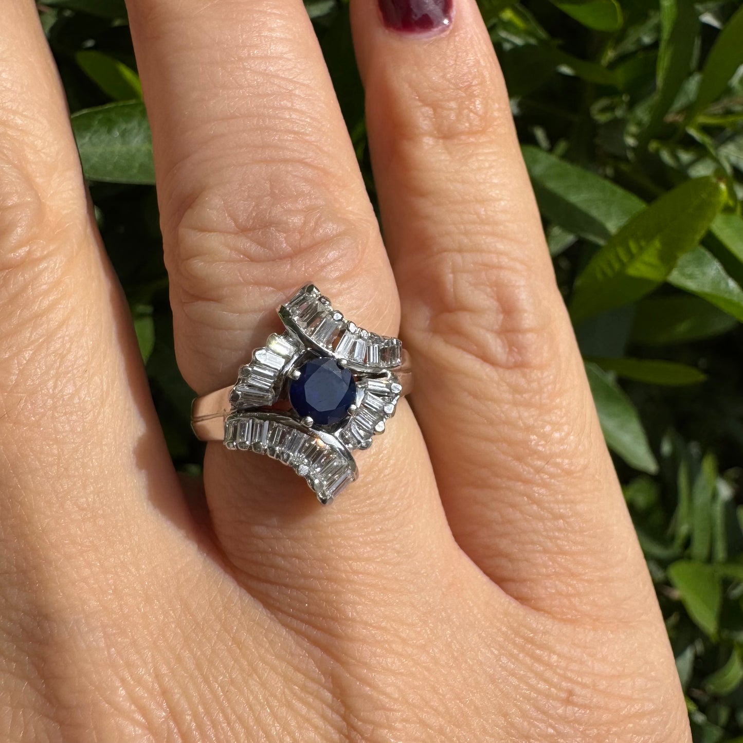 14K gold ring set with a round deep blue sapphire at the center, surrounded by baguette cut Diamonds