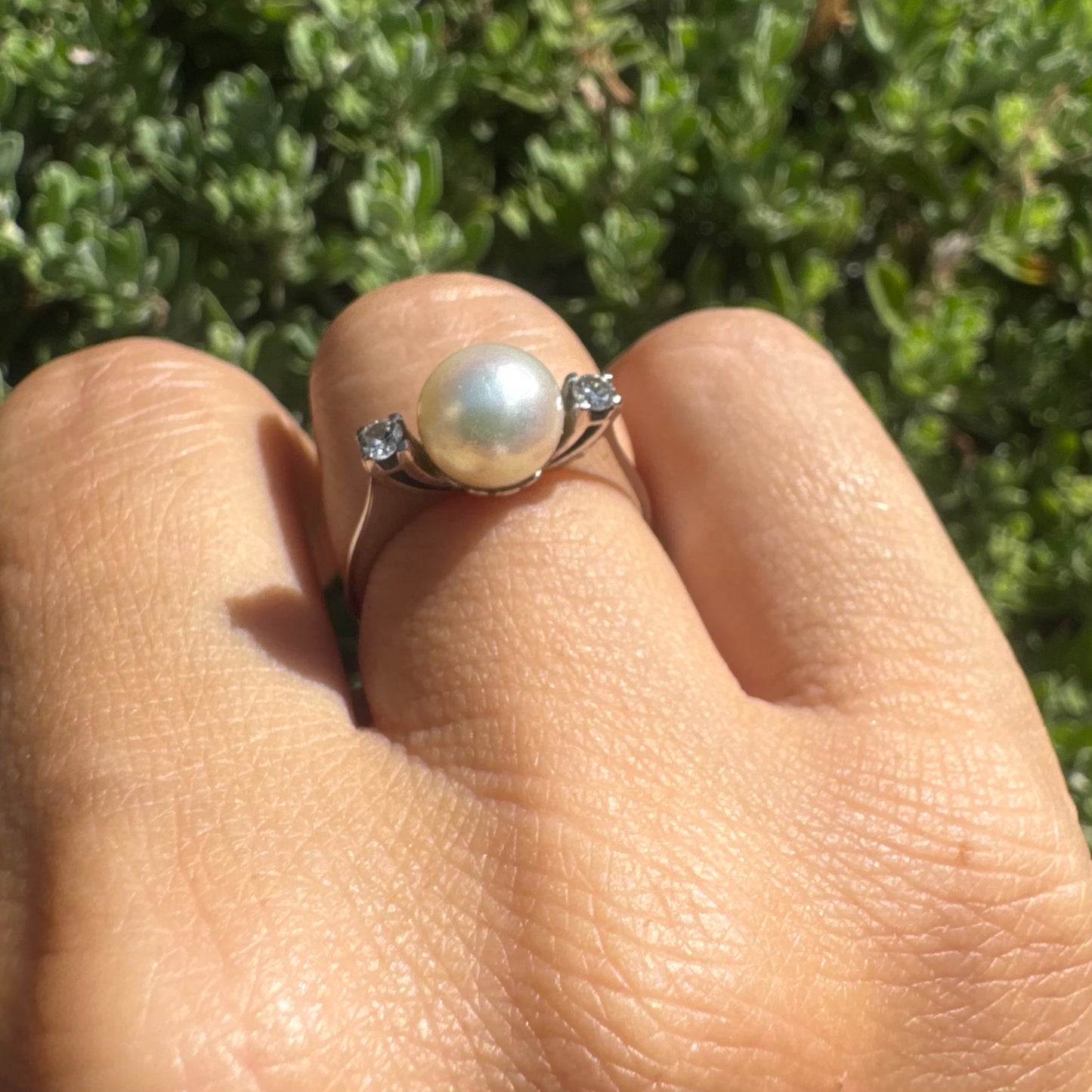 18K gold ring featuring a round Pearl at the center, flanked by two Diamonds.