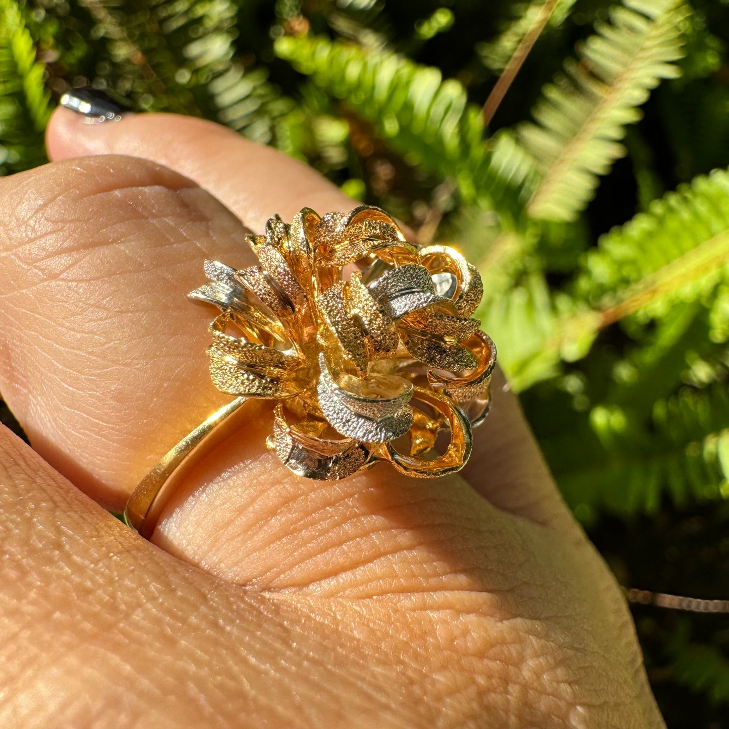18K gold ring set with intricately textured loops in yellow, white, and rose gold, forming a bold floral-inspired sculptural design.